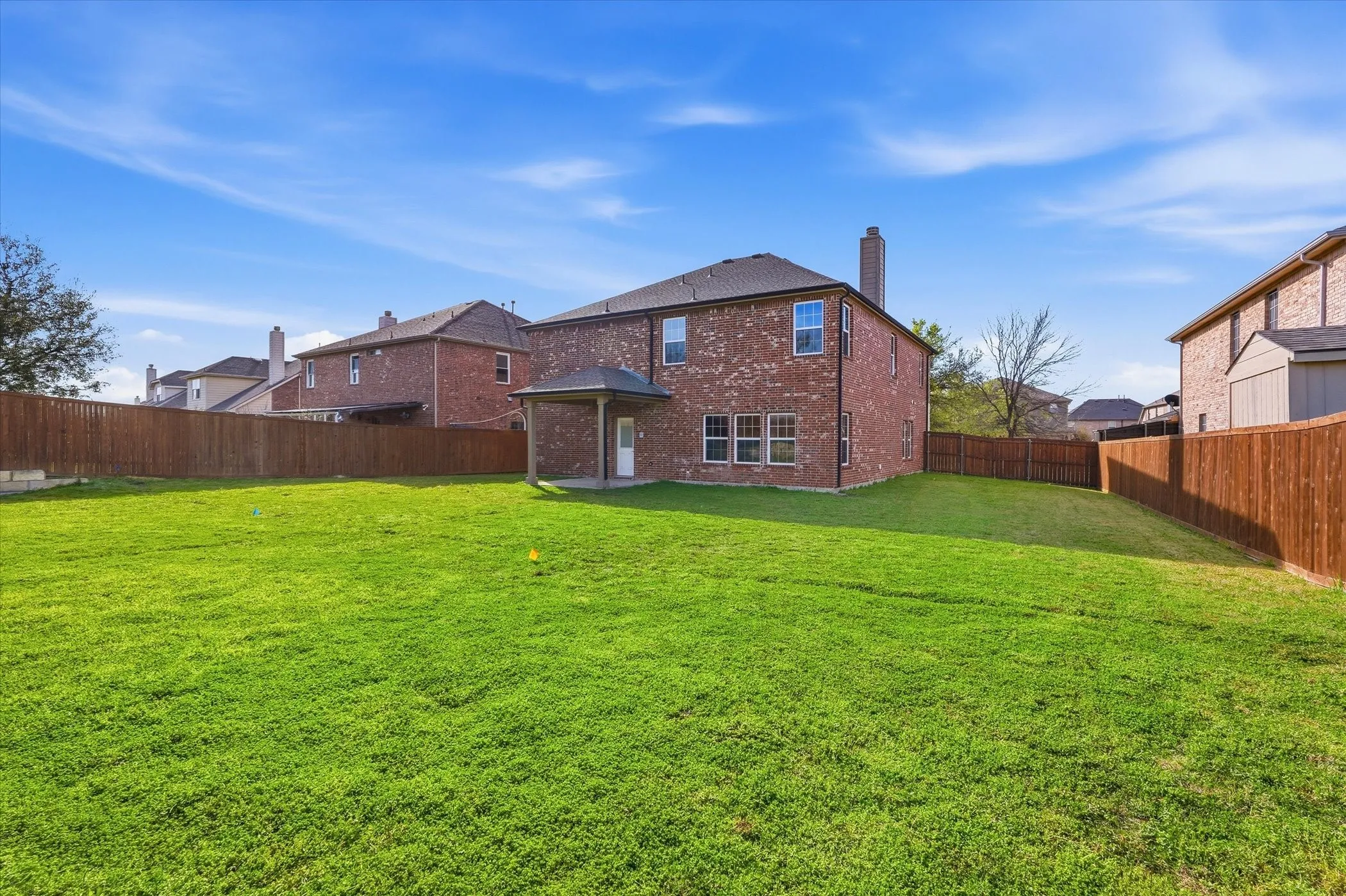 Back of house featuring a chimney, a patio area, brick siding, and a fenced backyard