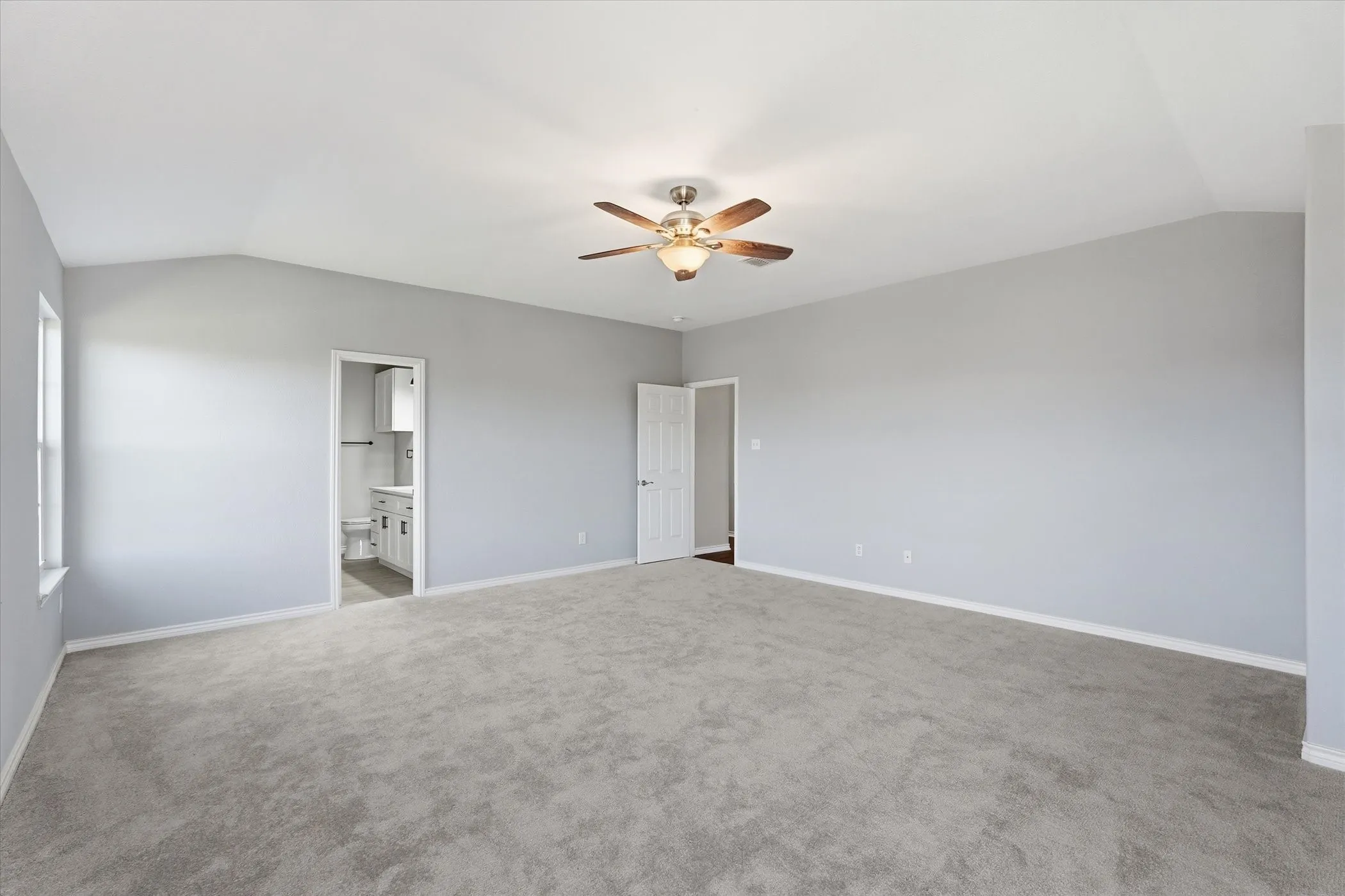 Unfurnished bedroom with carpet flooring, a ceiling fan, and ensuite bath