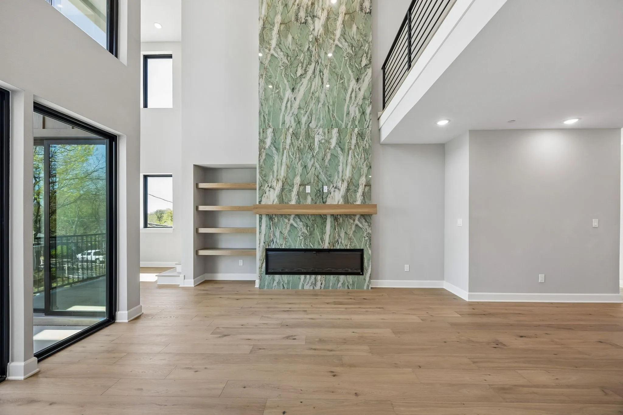 Unfurnished living room with a high ceiling, a large fireplace, light wood finished floors, plenty of natural light, and recessed lighting