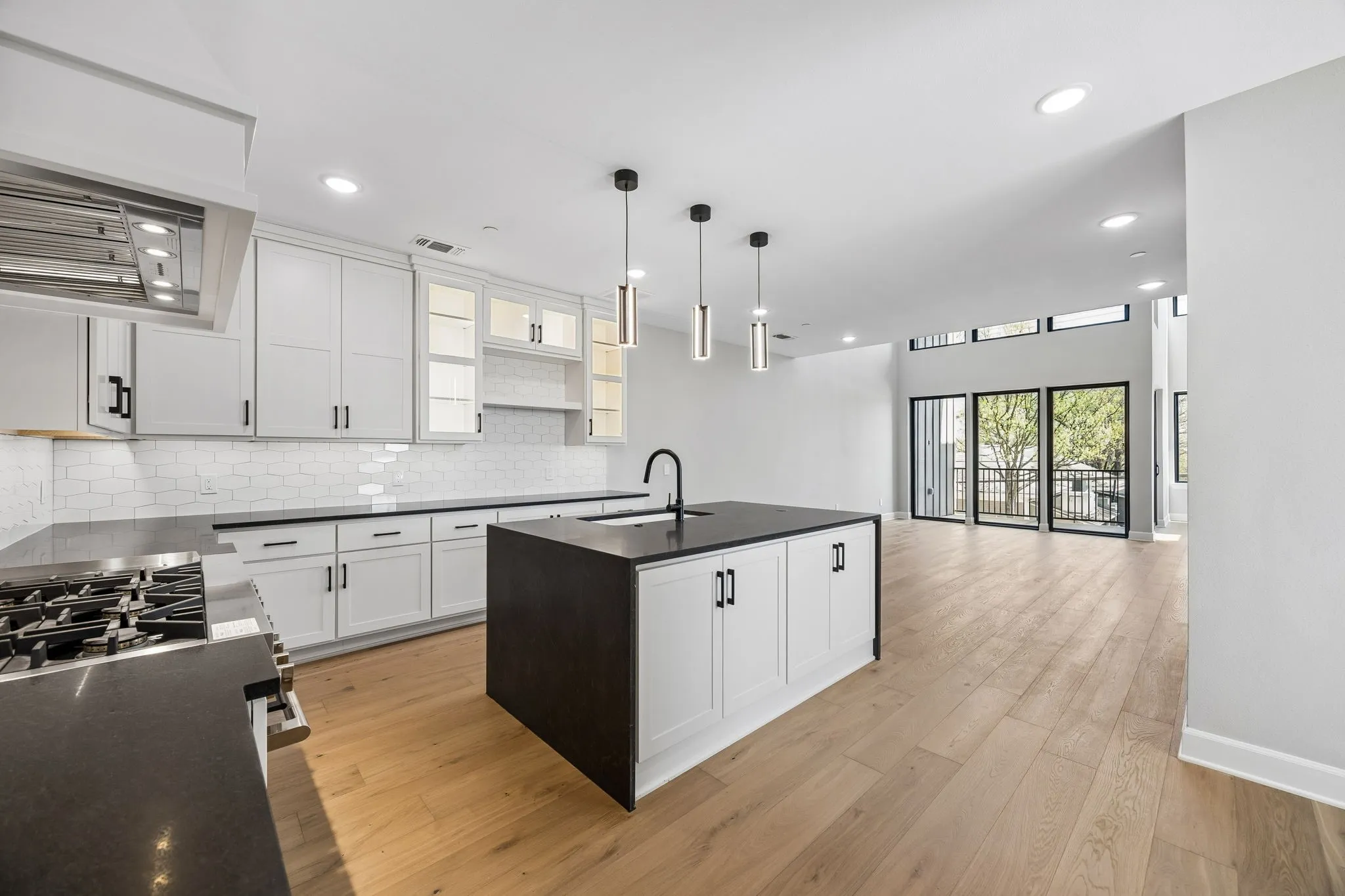 Kitchen with a kitchen island with sink, white cabinetry, stainless steel range with gas cooktop, light wood-type flooring, and open floor plan