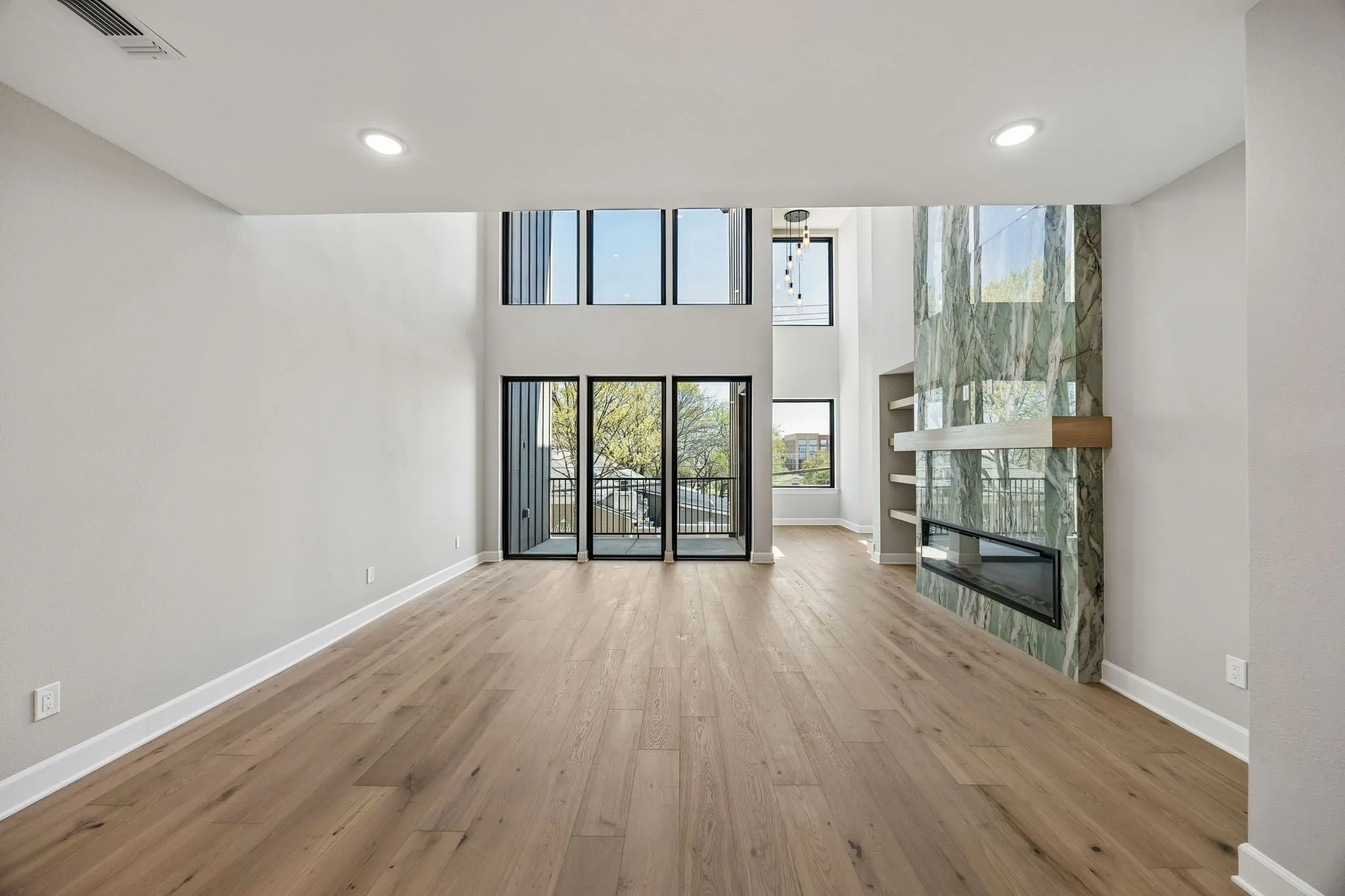 Unfurnished living room with a fireplace, a high ceiling, light wood finished floors, recessed lighting, and built in shelves