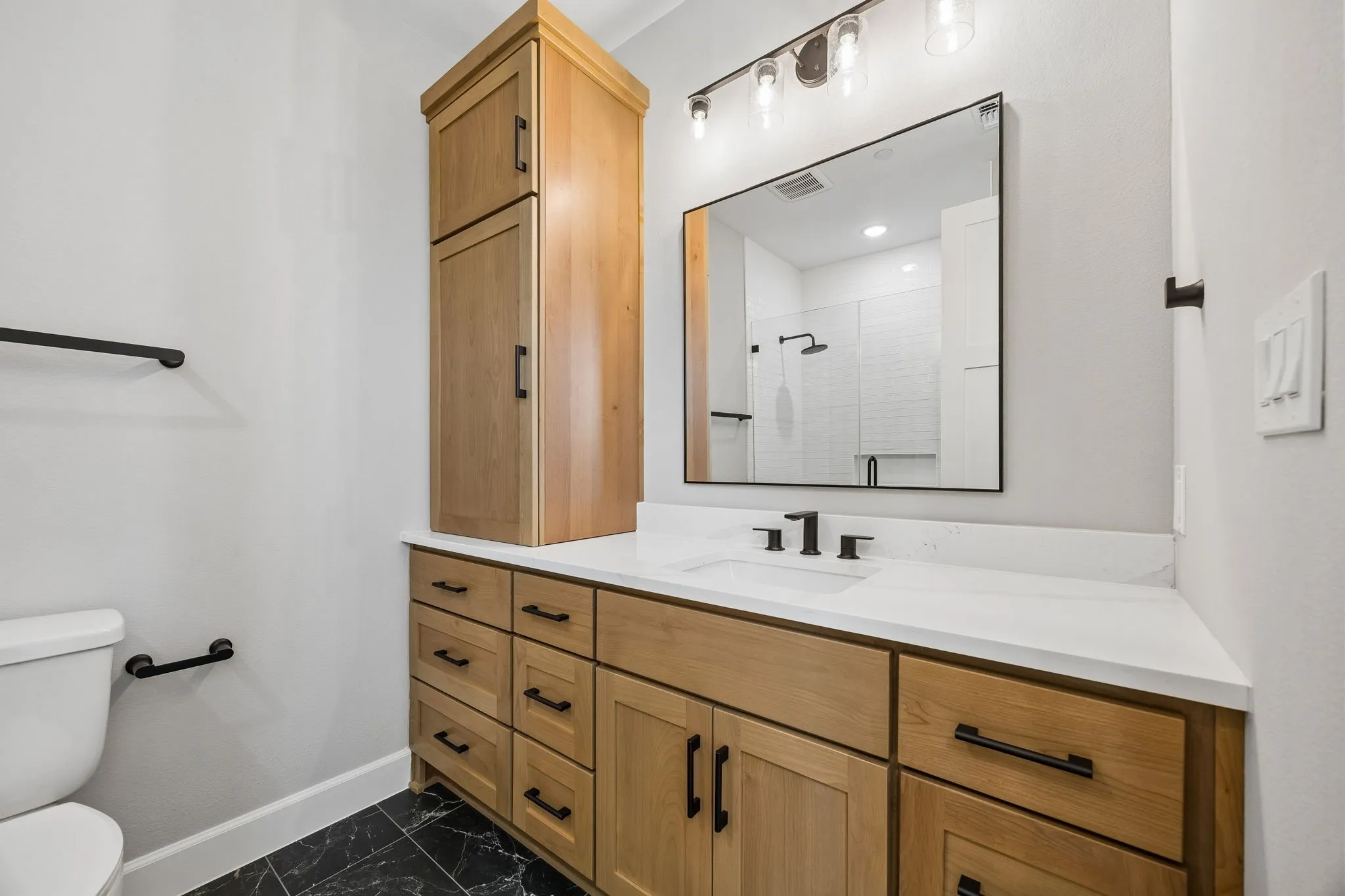 Bathroom with vanity, a shower stall, and dark marble finish floors