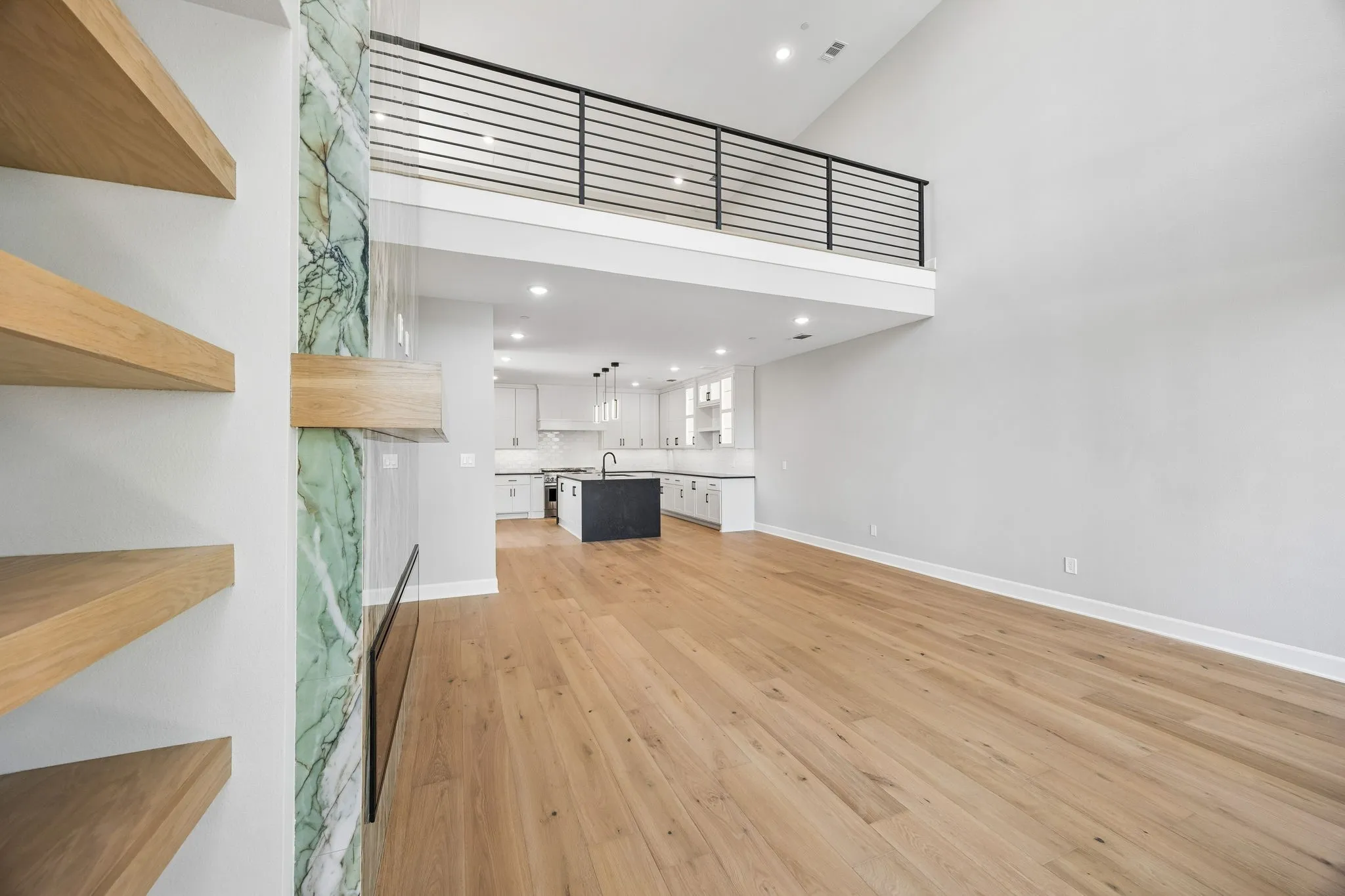 Unfurnished living room featuring a high ceiling, light wood-style floors, and recessed lighting
