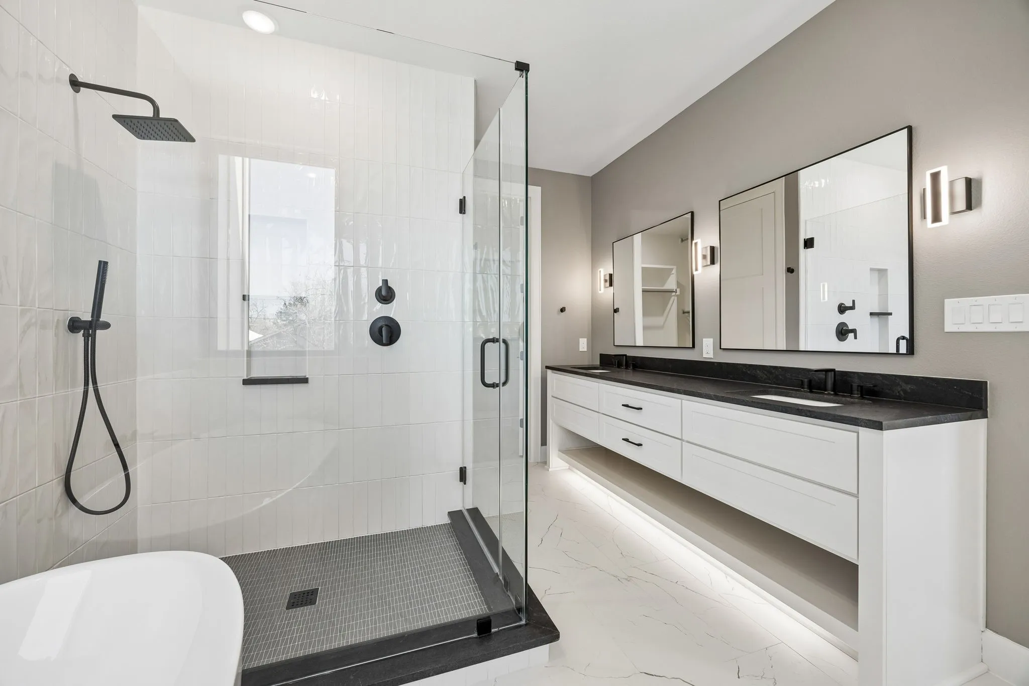 Bathroom with double vanity, a freestanding tub, a stall shower, and light marble finish floors
