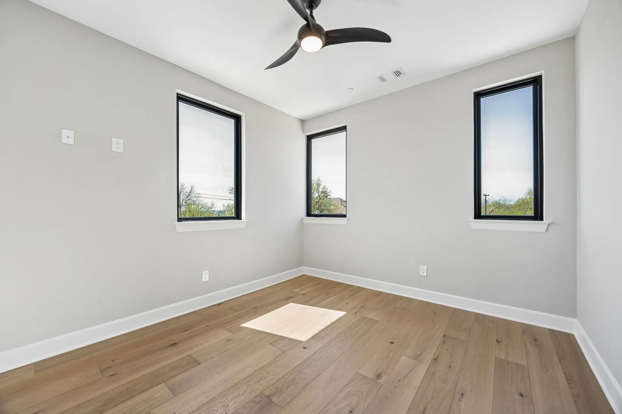 Empty room with light wood finished floors and a ceiling fan