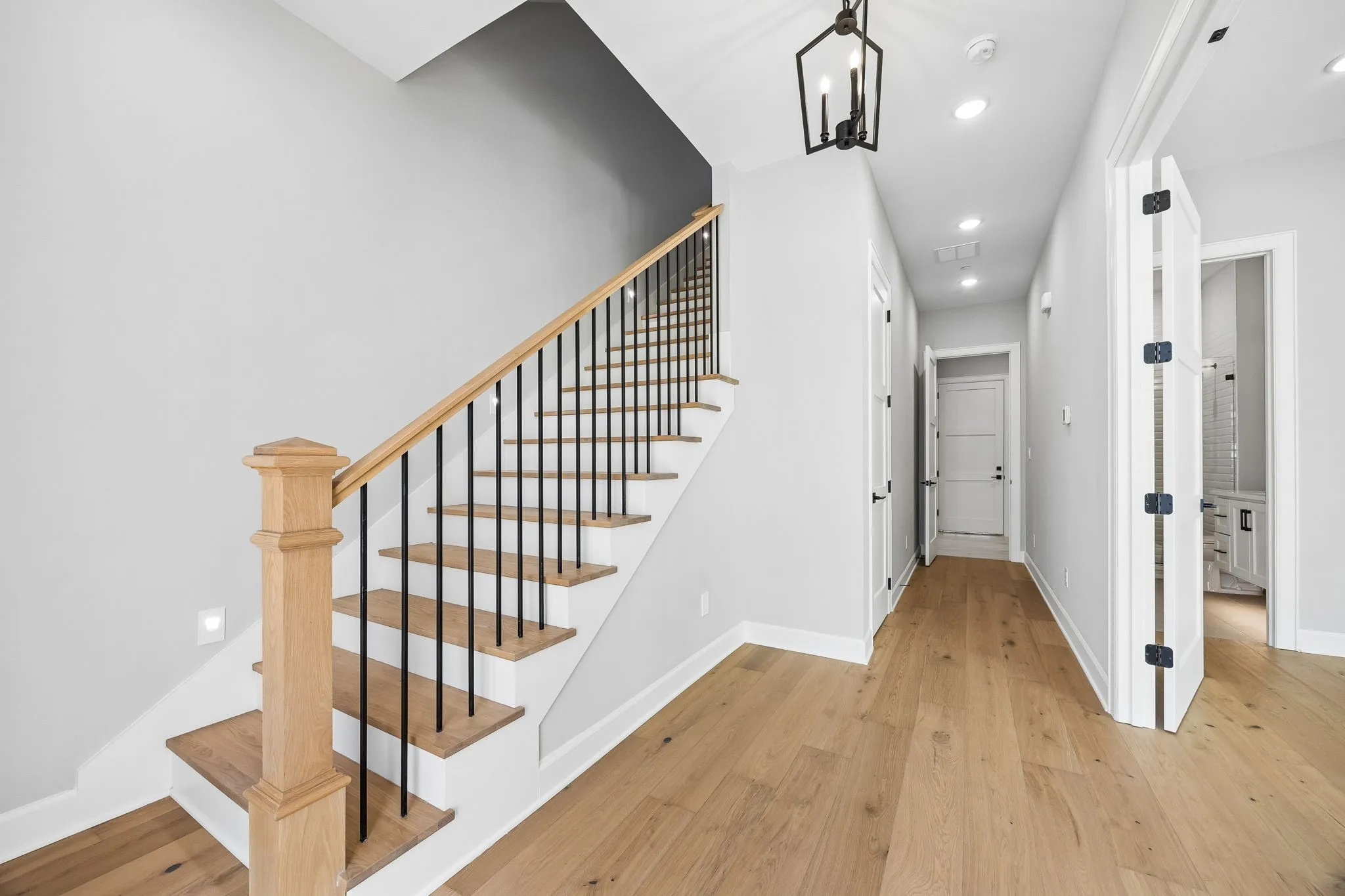 Staircase featuring wood finished floors and hanging lights