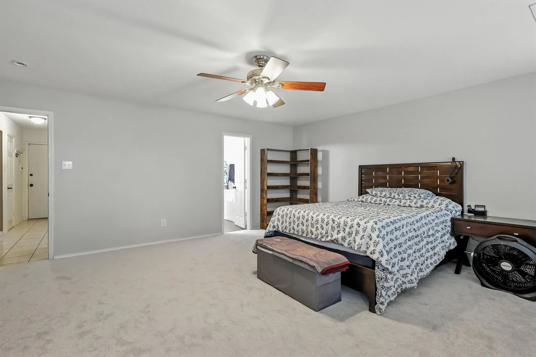 Carpeted bedroom with ceiling fan and ensuite bath