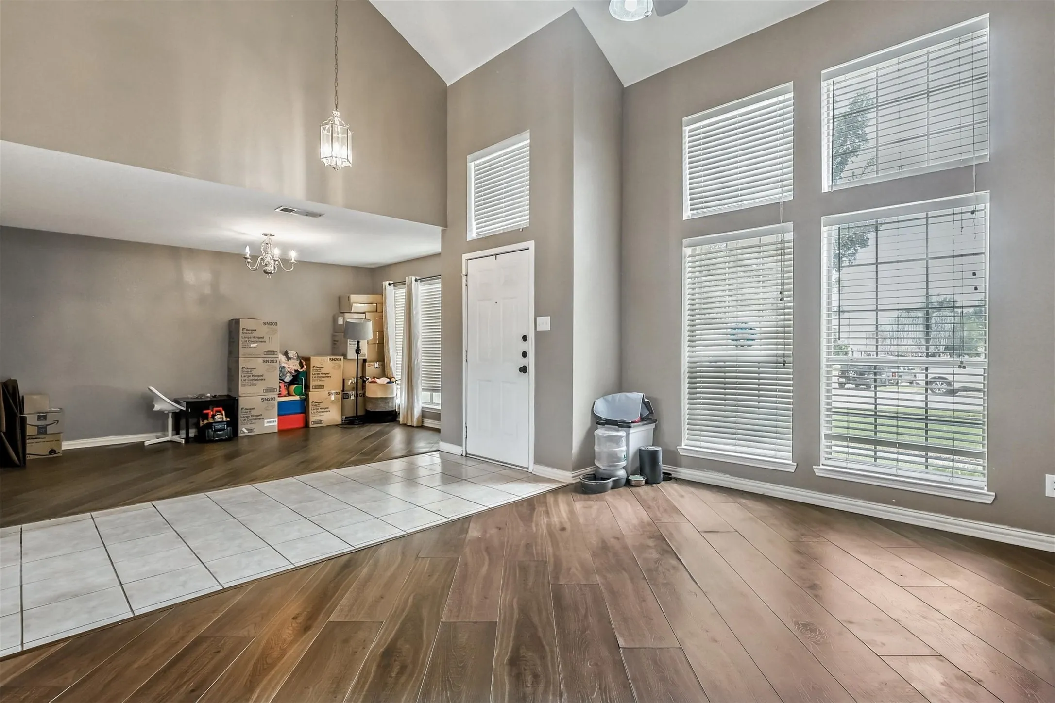 Foyer with high vaulted ceiling, a chandelier, and wood like floors