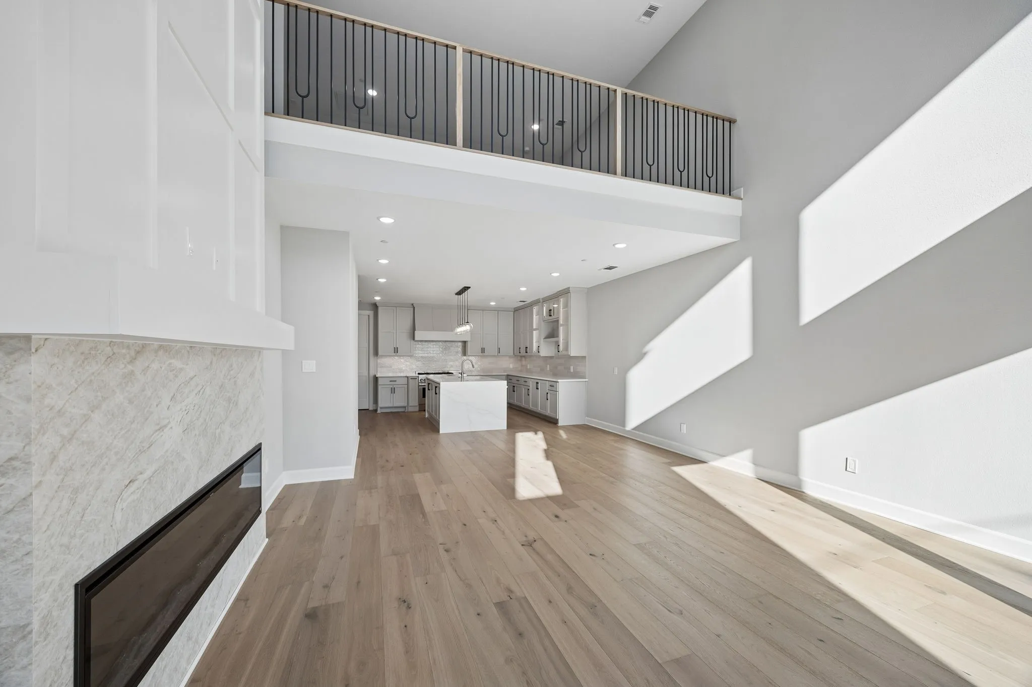 Unfurnished living room with light wood-type flooring, a glass covered fireplace, and a high ceiling