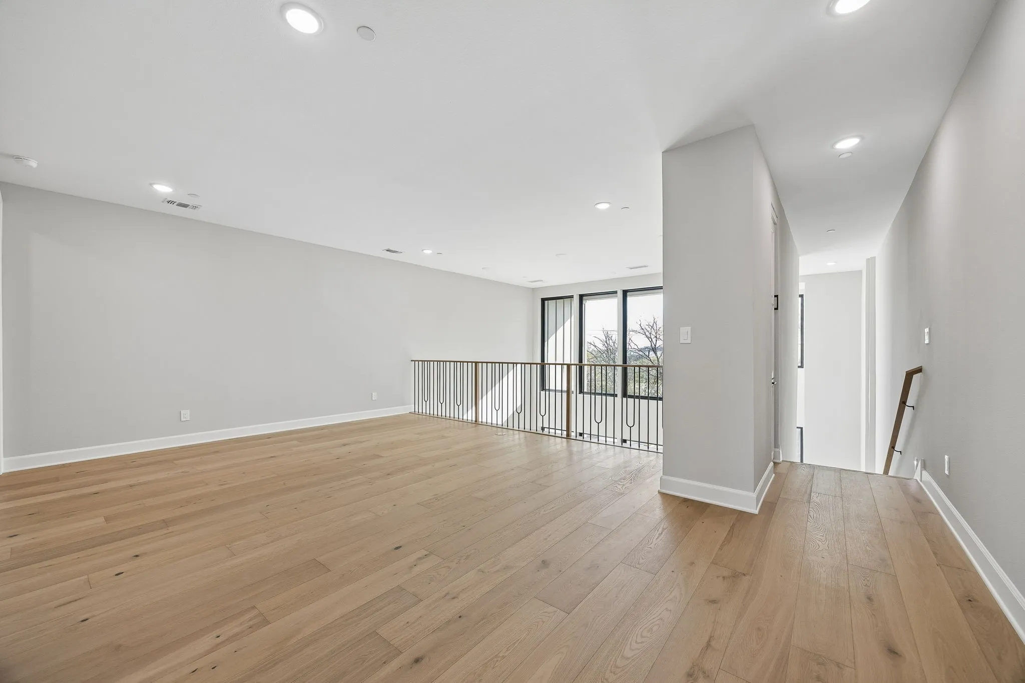 Empty room featuring light wood-style flooring, expansive windows, and recessed lighting
