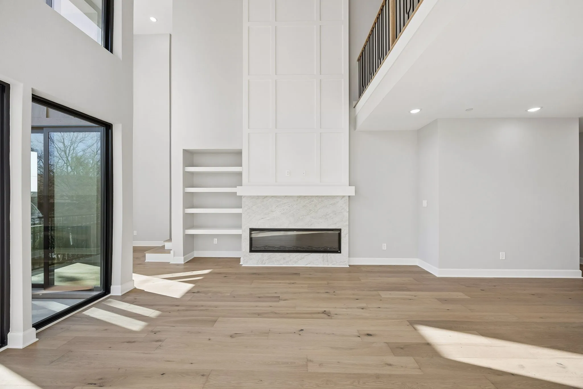 Unfurnished living room featuring a high ceiling, light wood-style floors, a fireplace, recessed lighting, and built in shelves