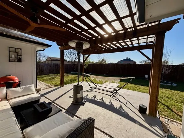 Fenced backyard featuring a patio area, an outdoor living space, a pergola, and a ceiling fan