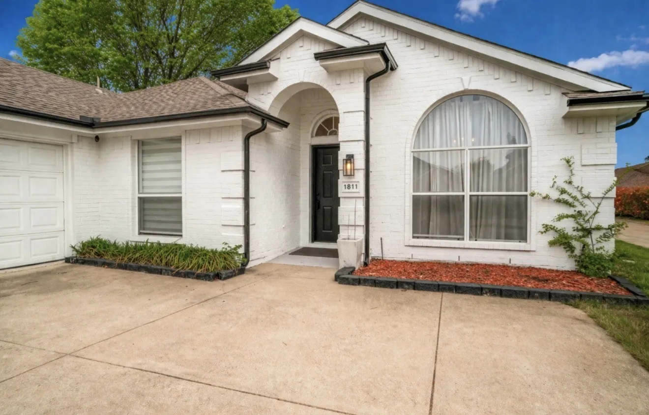 Doorway to property with brick siding, a garage, and a shingled roof