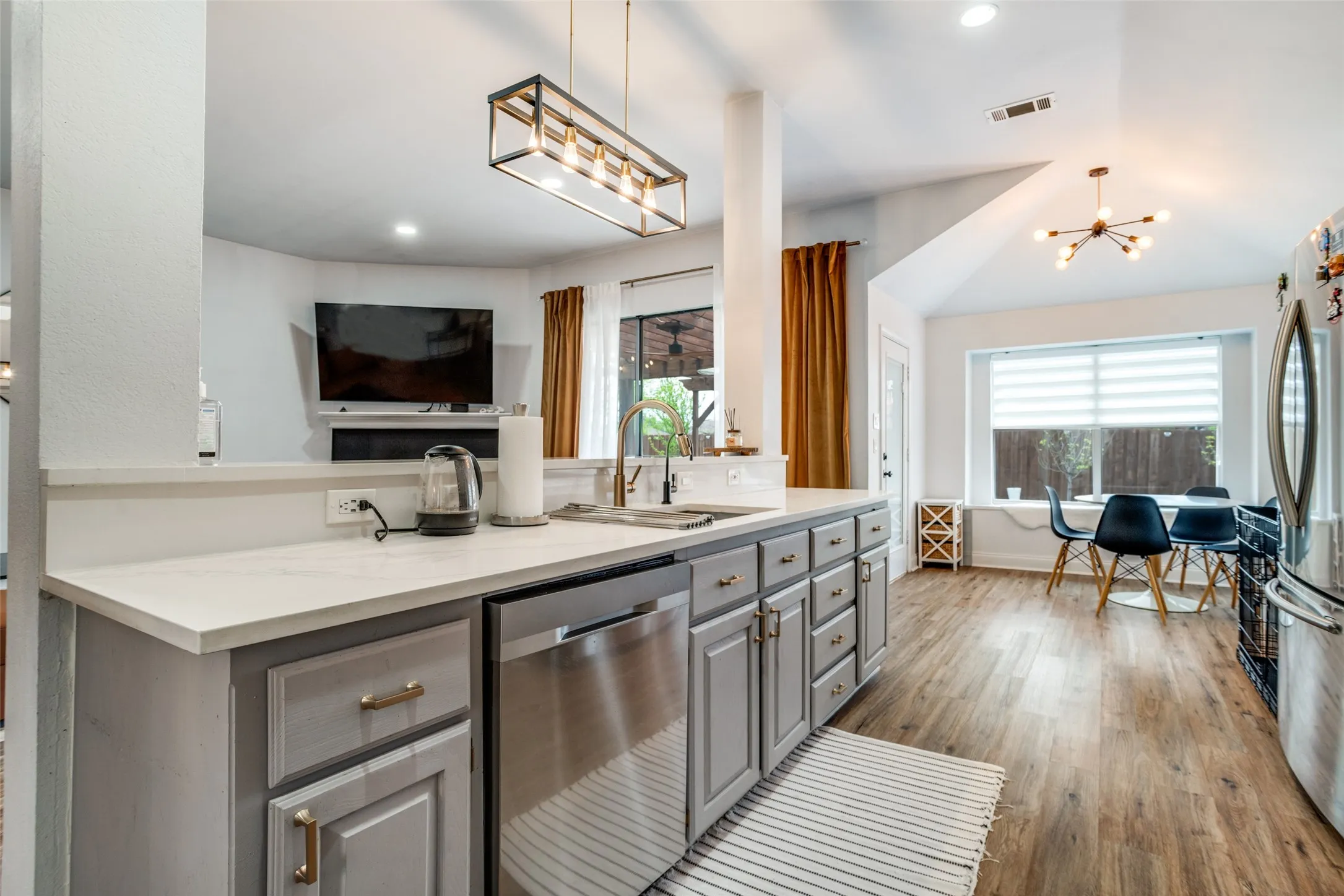 Kitchen featuring gray cabinetry, stainless steel appliances, a chandelier, dark wood finished floors, and plenty of natural light