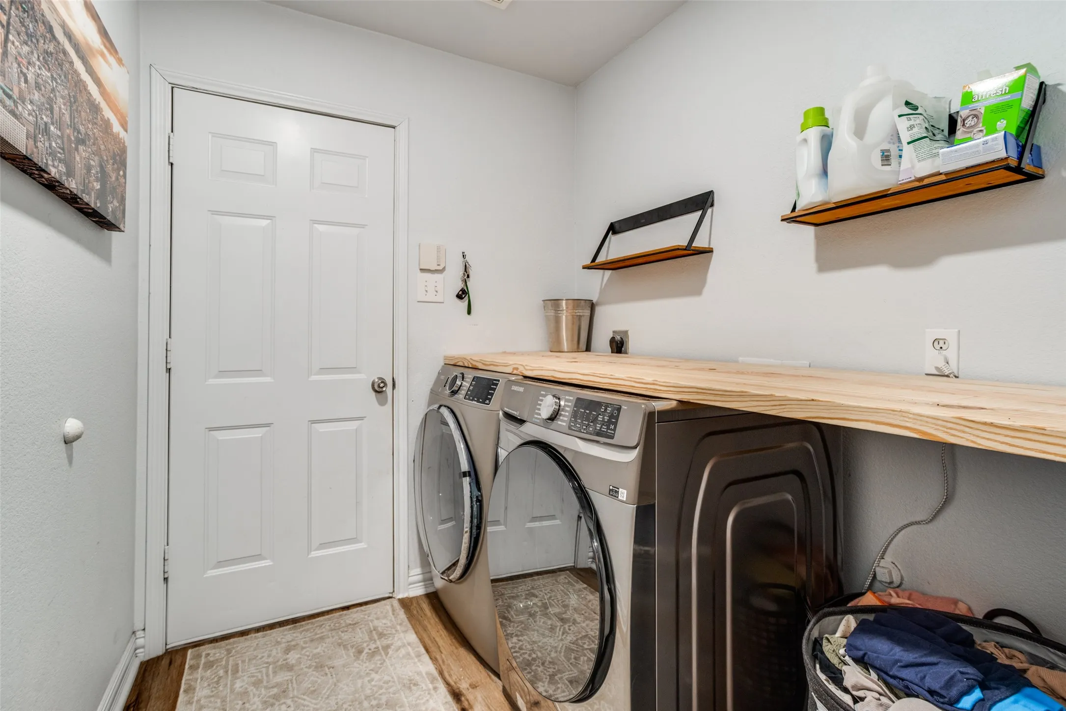 Laundry room with independent washer and dryer and light wood-style flooring