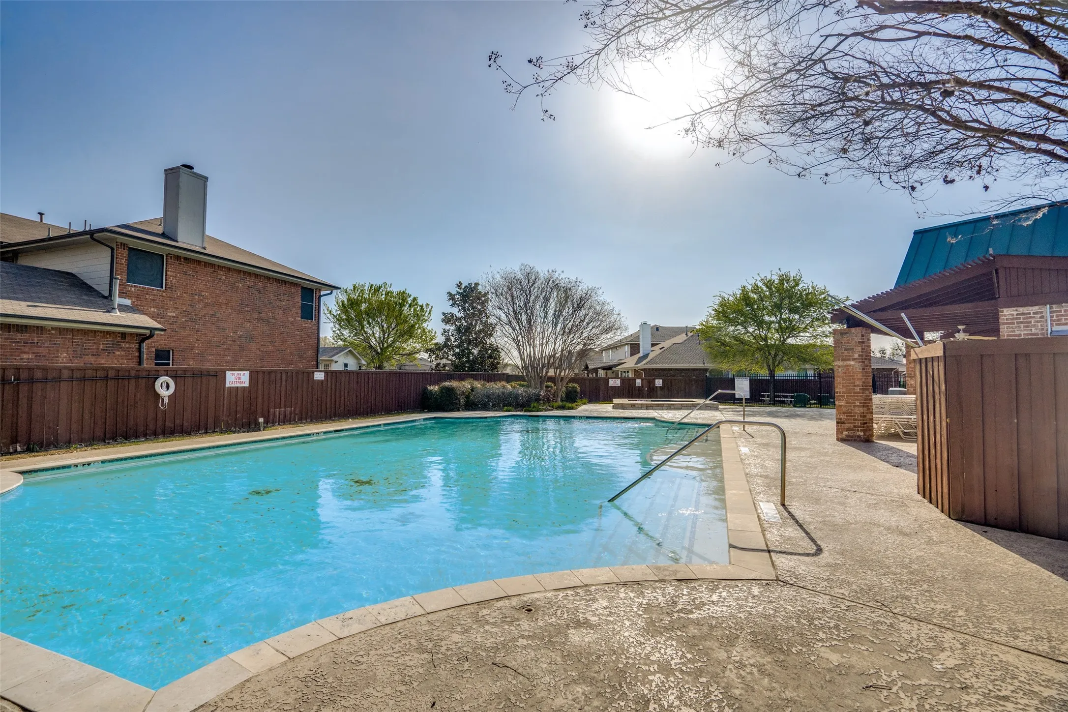 Community pool with a patio area and a fenced backyard
