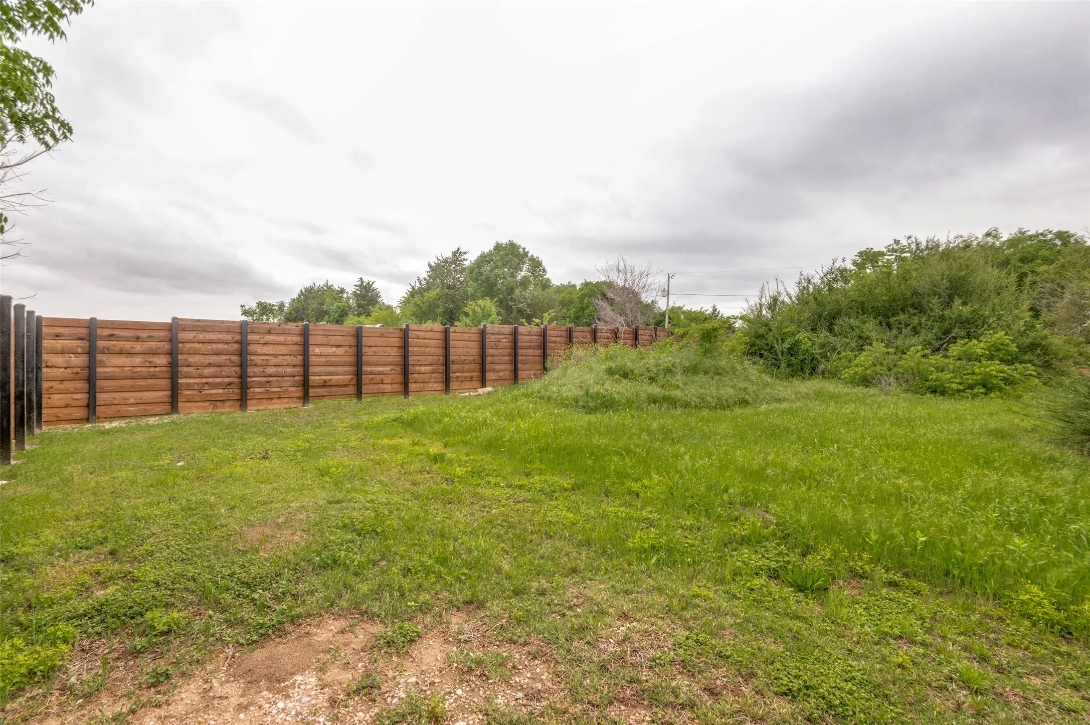 Expansive green space featuring a wood fence with horizontal planks and dark posts