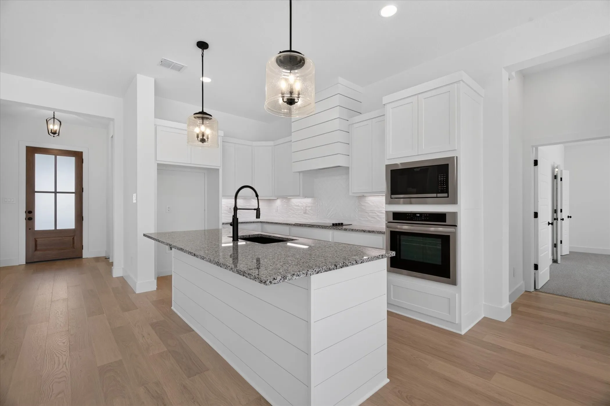 Kitchen island featuring a granite countertop, shiplap detailing, and pendant lighting