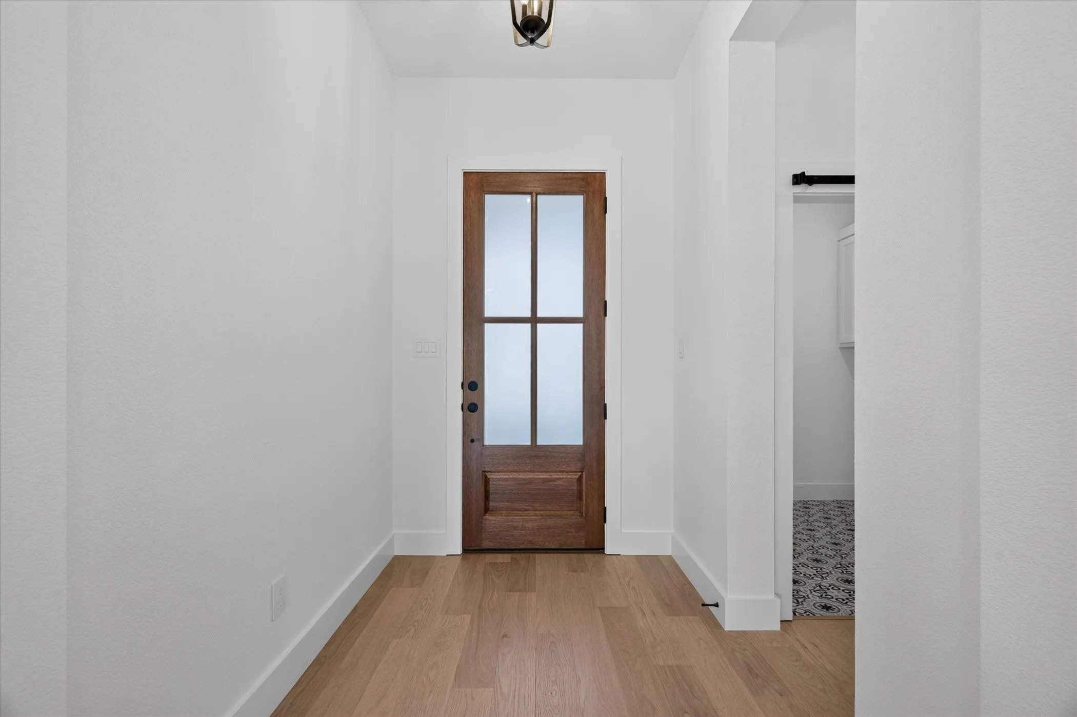 Entryway featuring a wood-finish door with frosted glass panels, wood-finish flooring, and a ceiling-mounted fixture