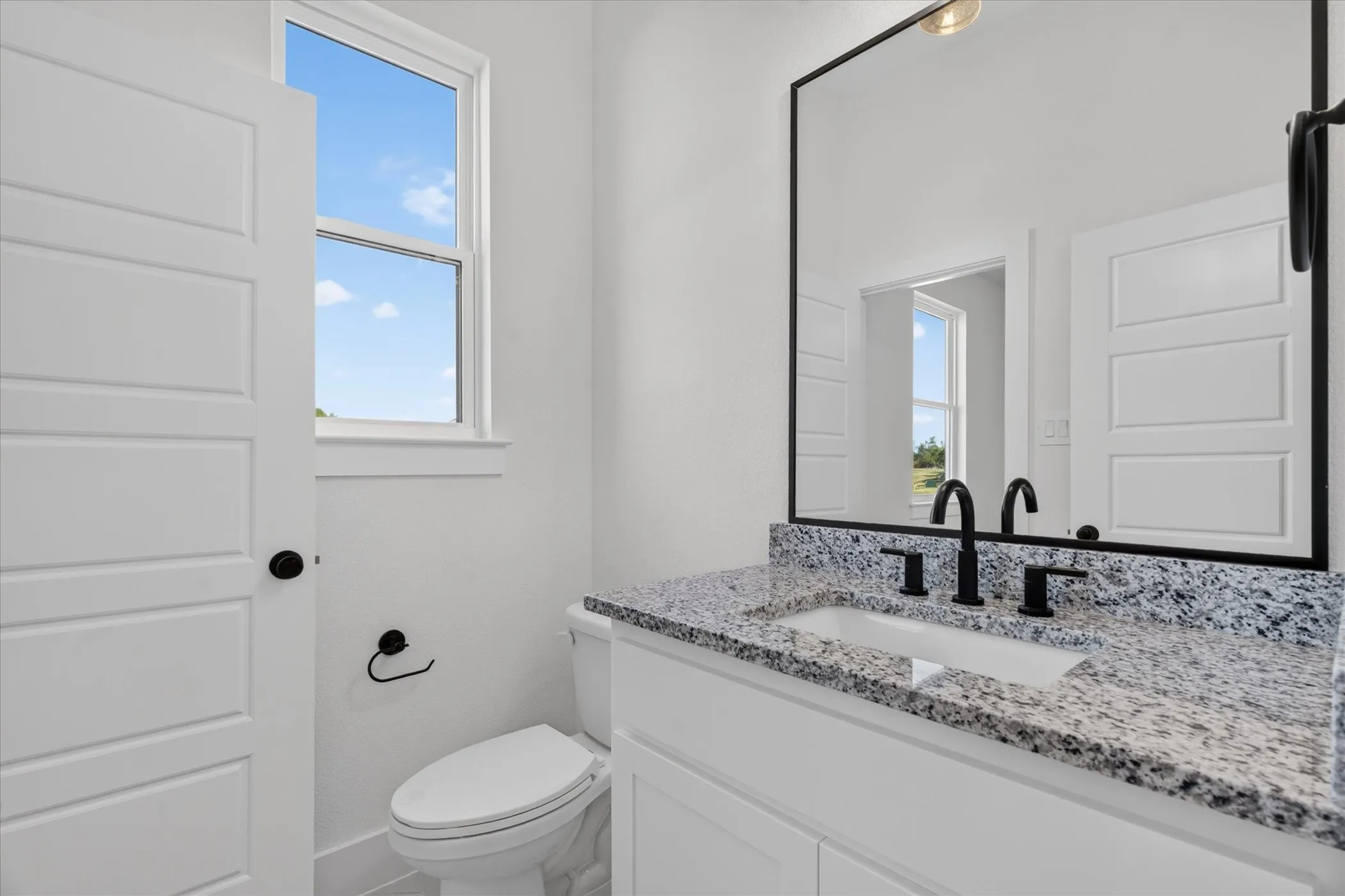 White vanity with granite countertop, integrated rectangular sink, and matte black fixtures