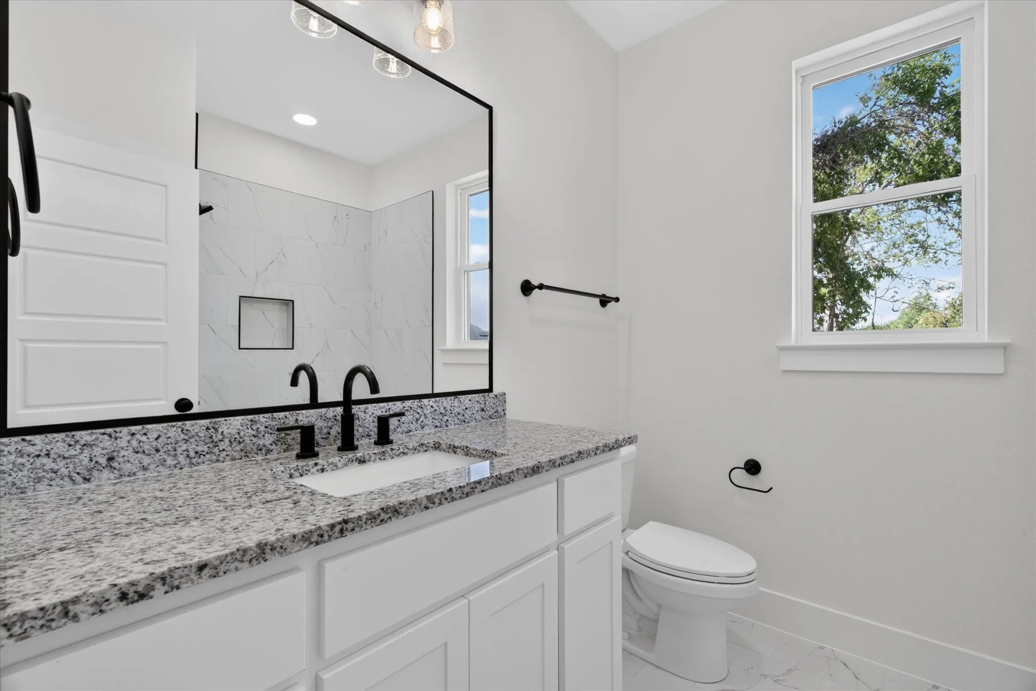 Spacious vanity with a speckled countertop, undermount sink, and matte black fixtures