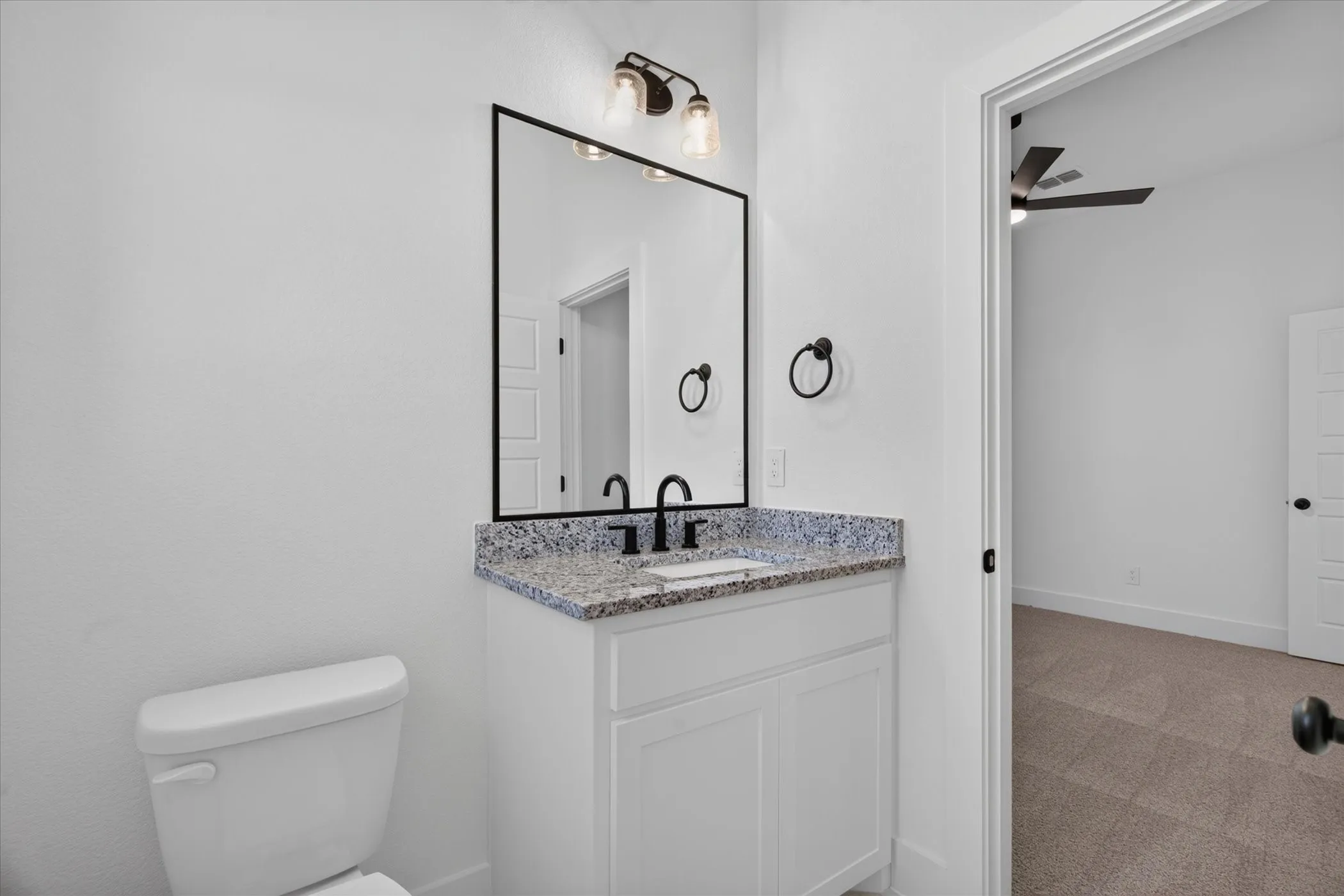 White vanity with a granite countertop and black faucet