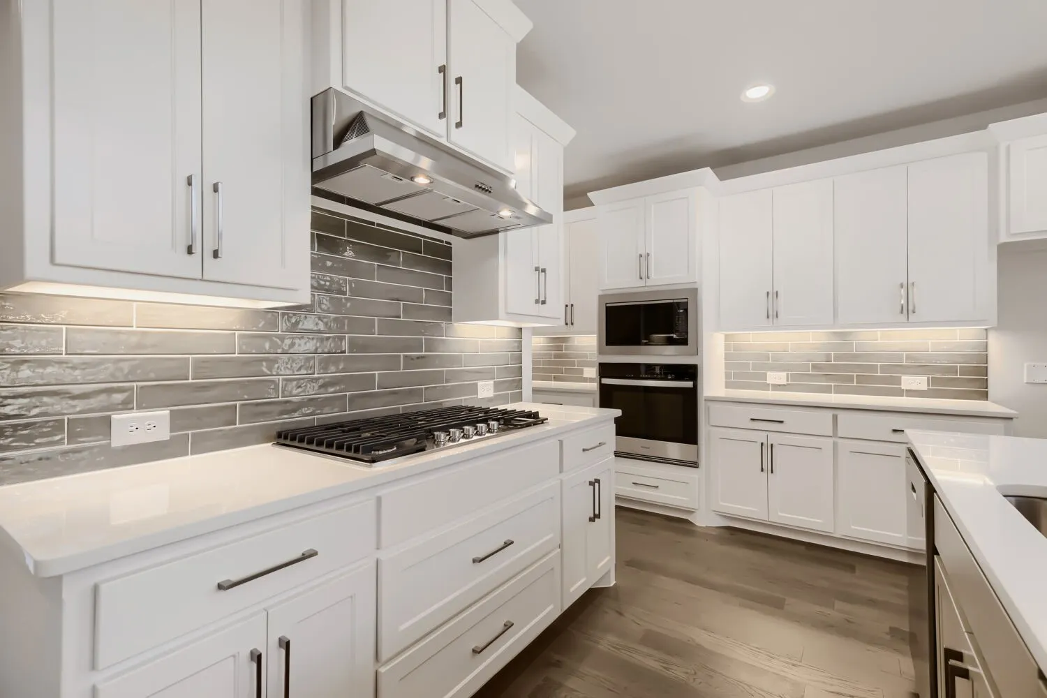 Modern kitchen featuring white cabinetry, a built-in oven and microwave, a gas range, quartz countertops, and wood-finish flooring