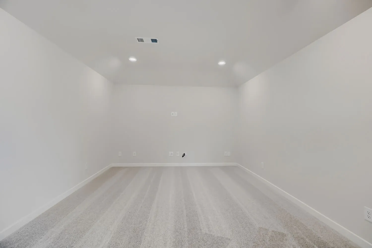 Spacious room featuring light gray carpeting, recessed lighting, white walls, white baseboards, and ceiling-mounted vents
