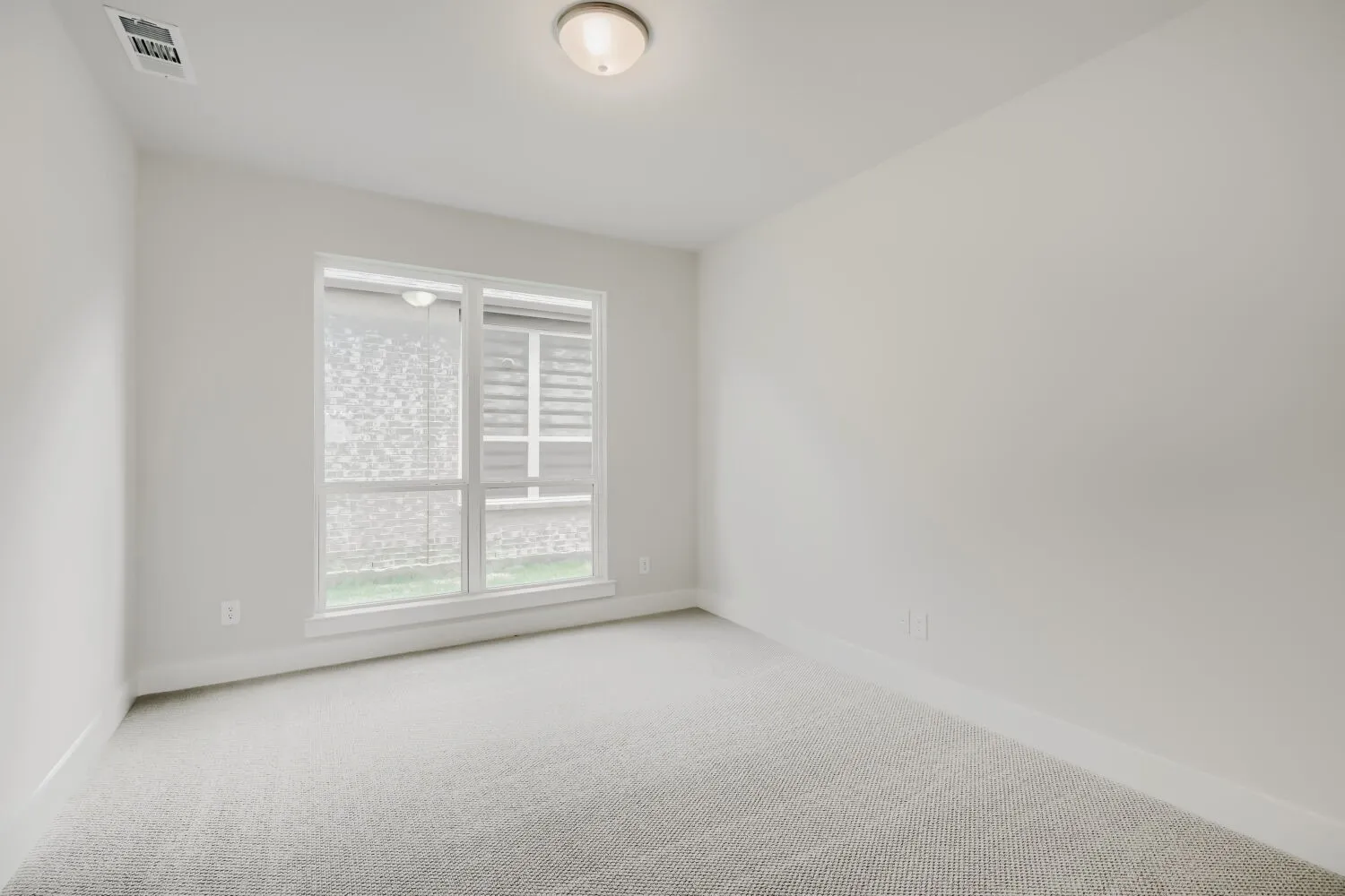 Neutral-toned room featuring a single window, recessed ceiling light, and light gray wall-to-wall carpeting
