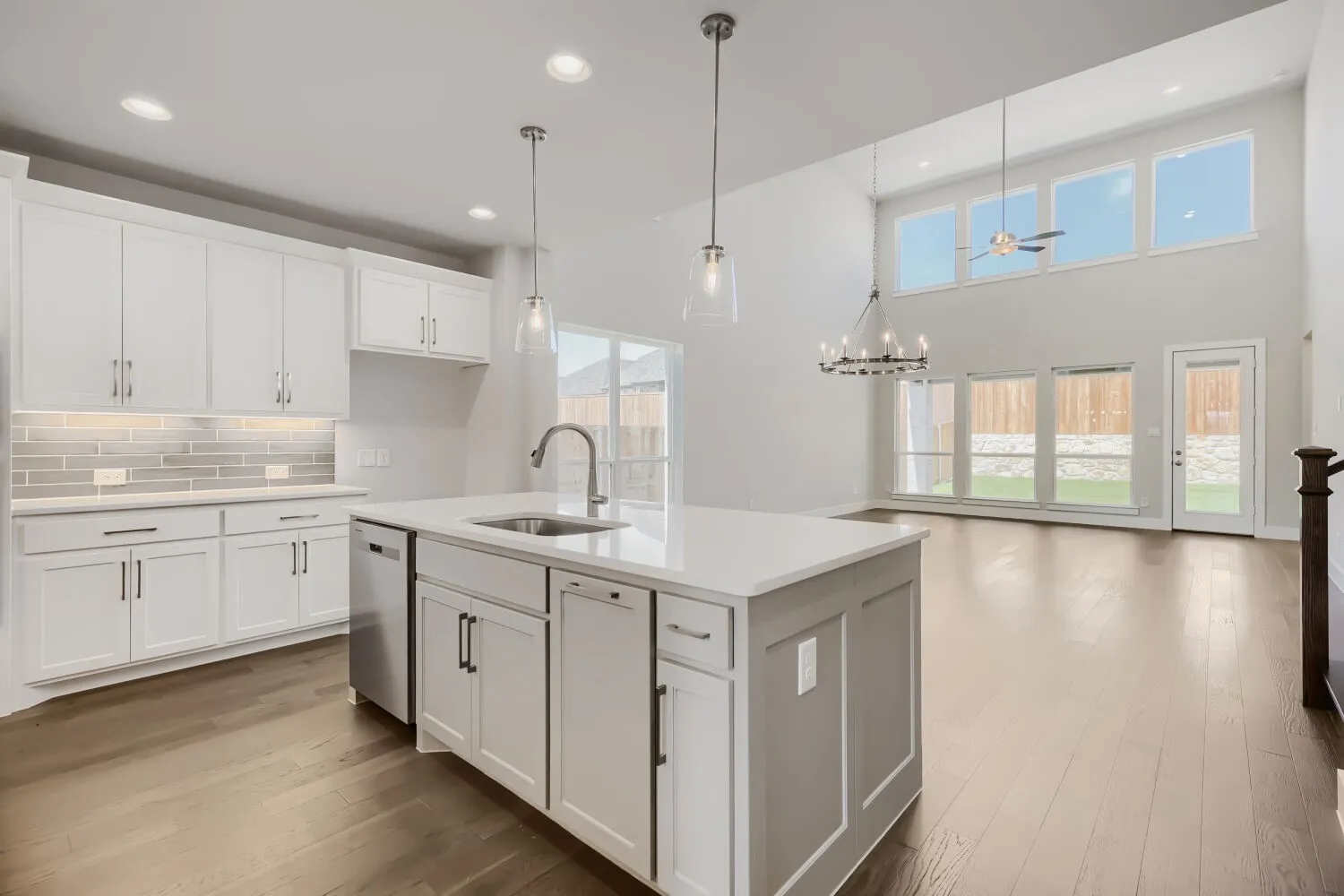 Open-concept living space with a kitchen island featuring a stainless steel sink and pendant lighting