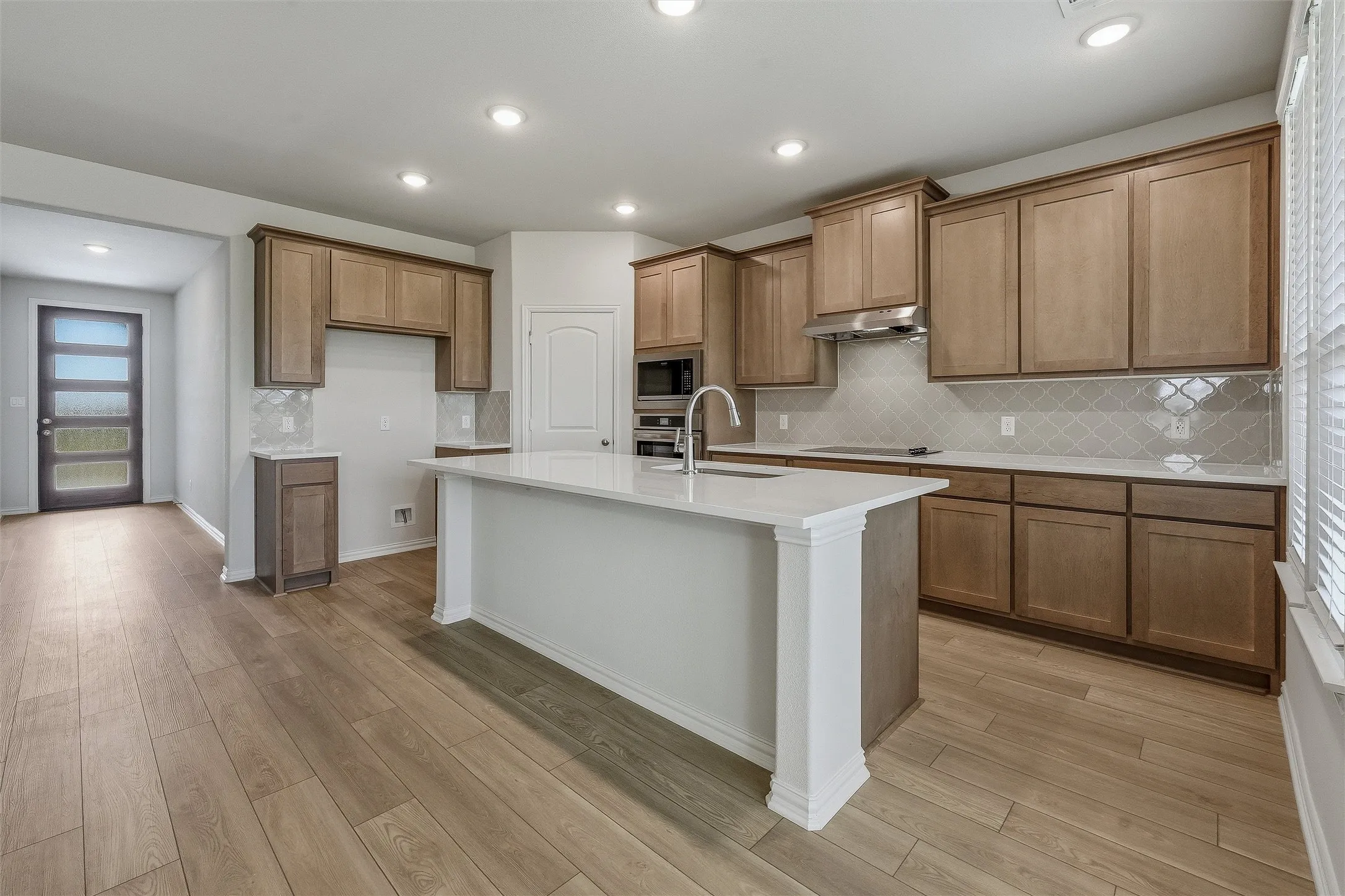 Kitchen featuring a central island with white countertop, integrated sink, and gooseneck faucet