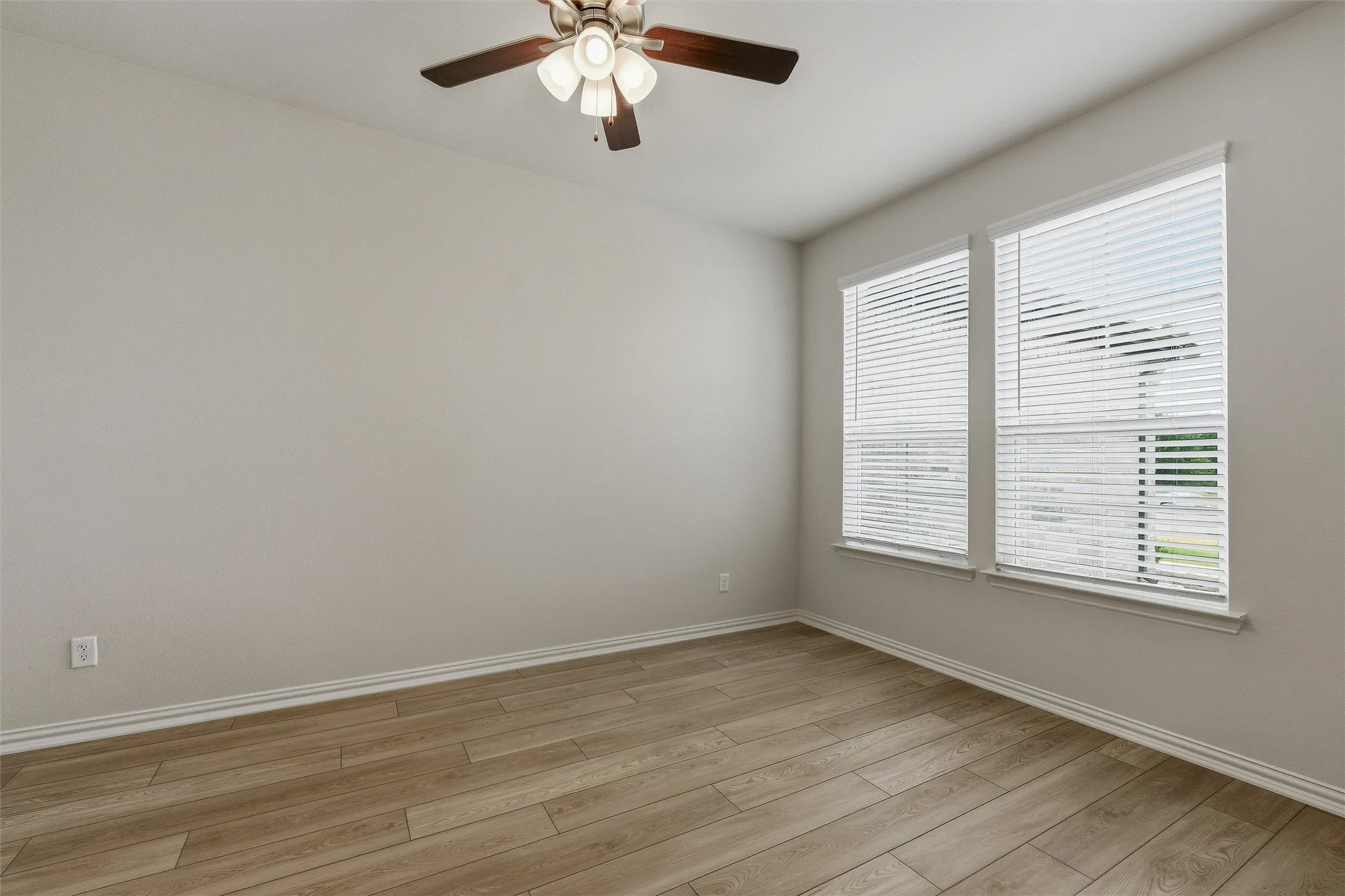Room featuring light-toned walls, wood-finish flooring, and white baseboards