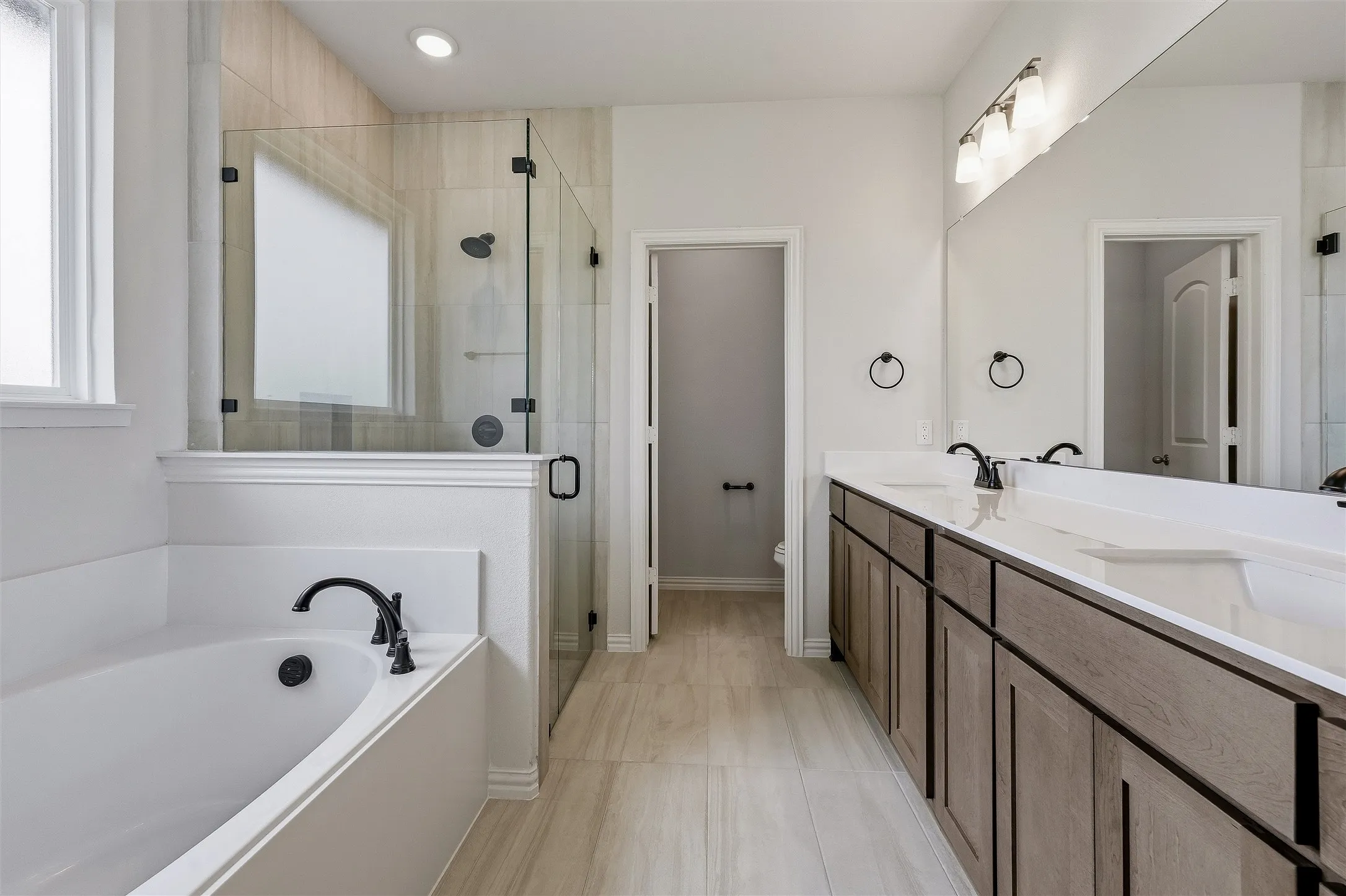 Bathroom featuring a built-in soaking tub, a walk-in shower with clear glass enclosure, and a double vanity with two undermount sinks