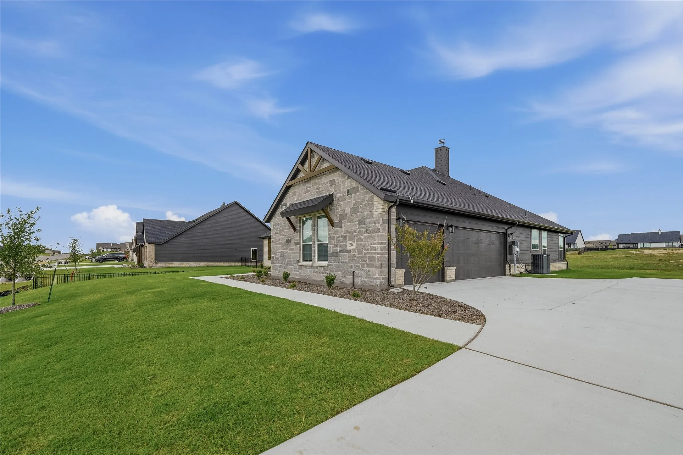Stone and siding exterior featuring a prominent two-car garage, dark shingle roof, and a stone chimney