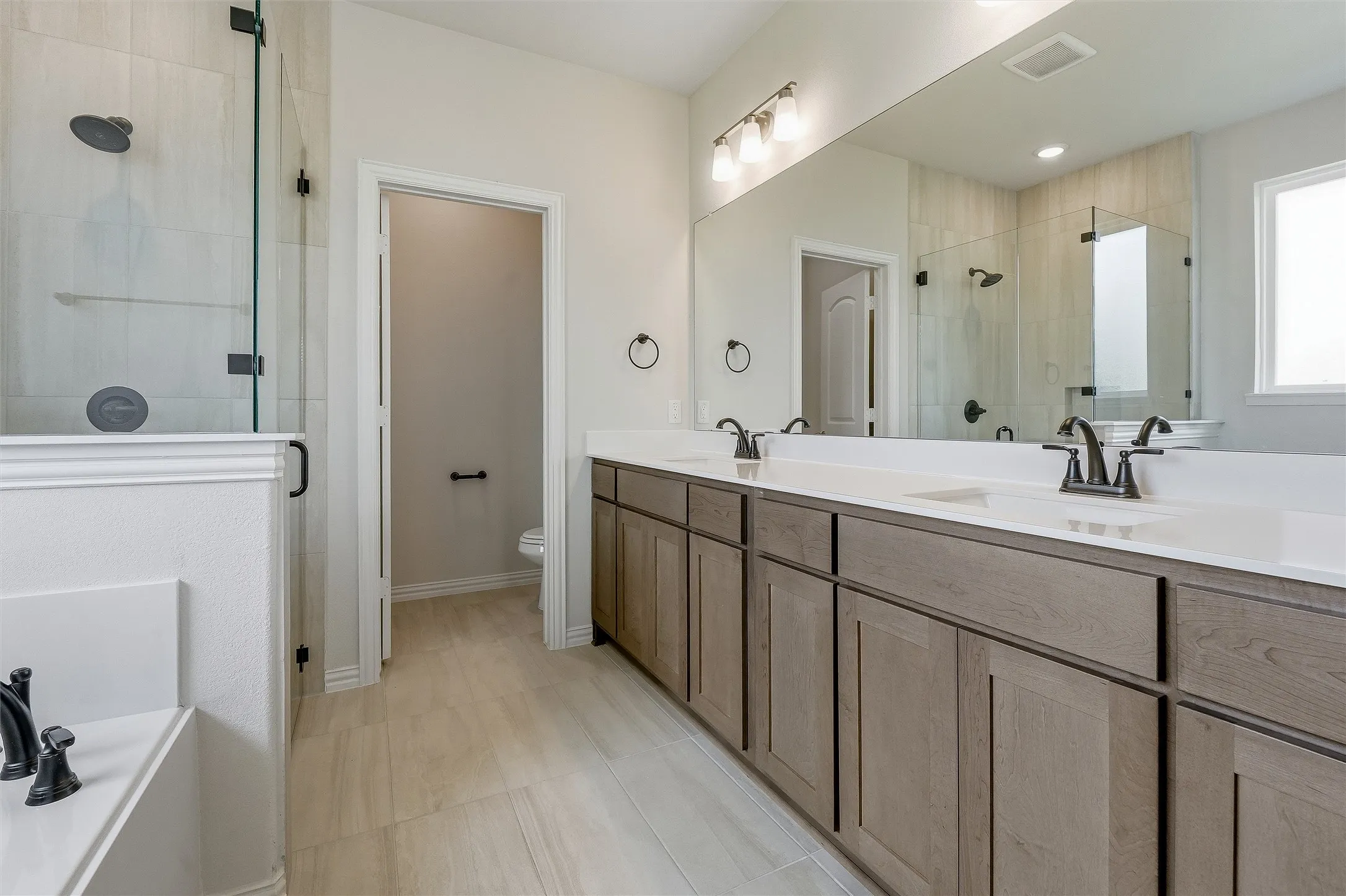 Bathroom featuring a dual vanity with light wood-finish cabinetry and white countertops