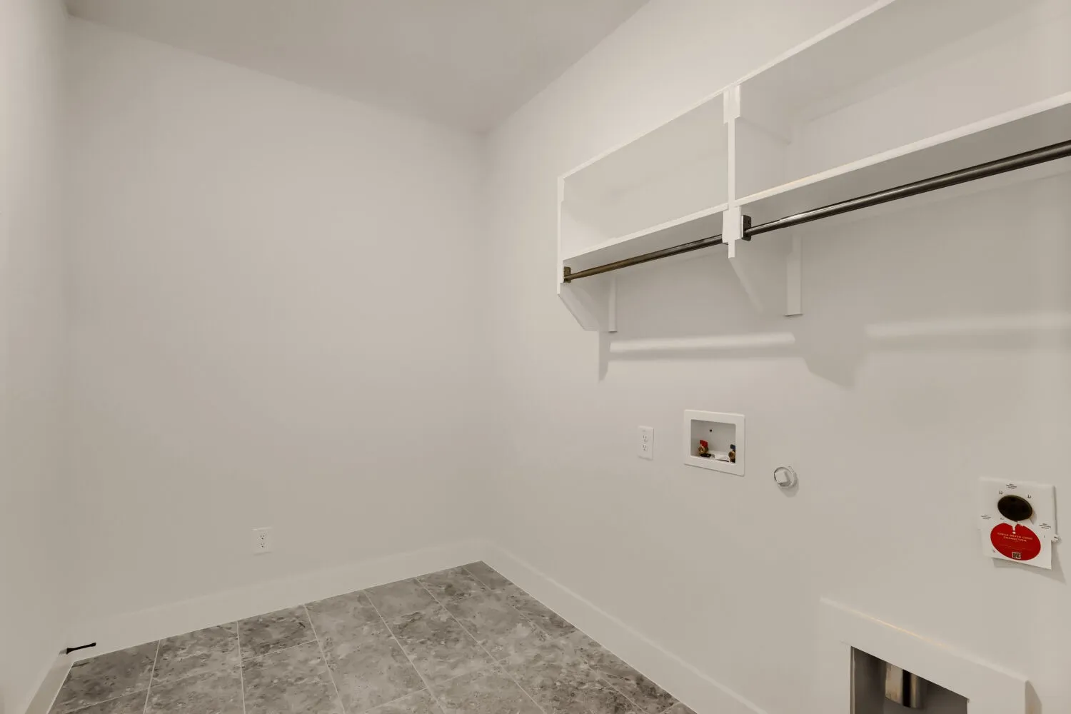 Dedicated utility room featuring tiled flooring, white walls, built-in shelving, and a hanging rod