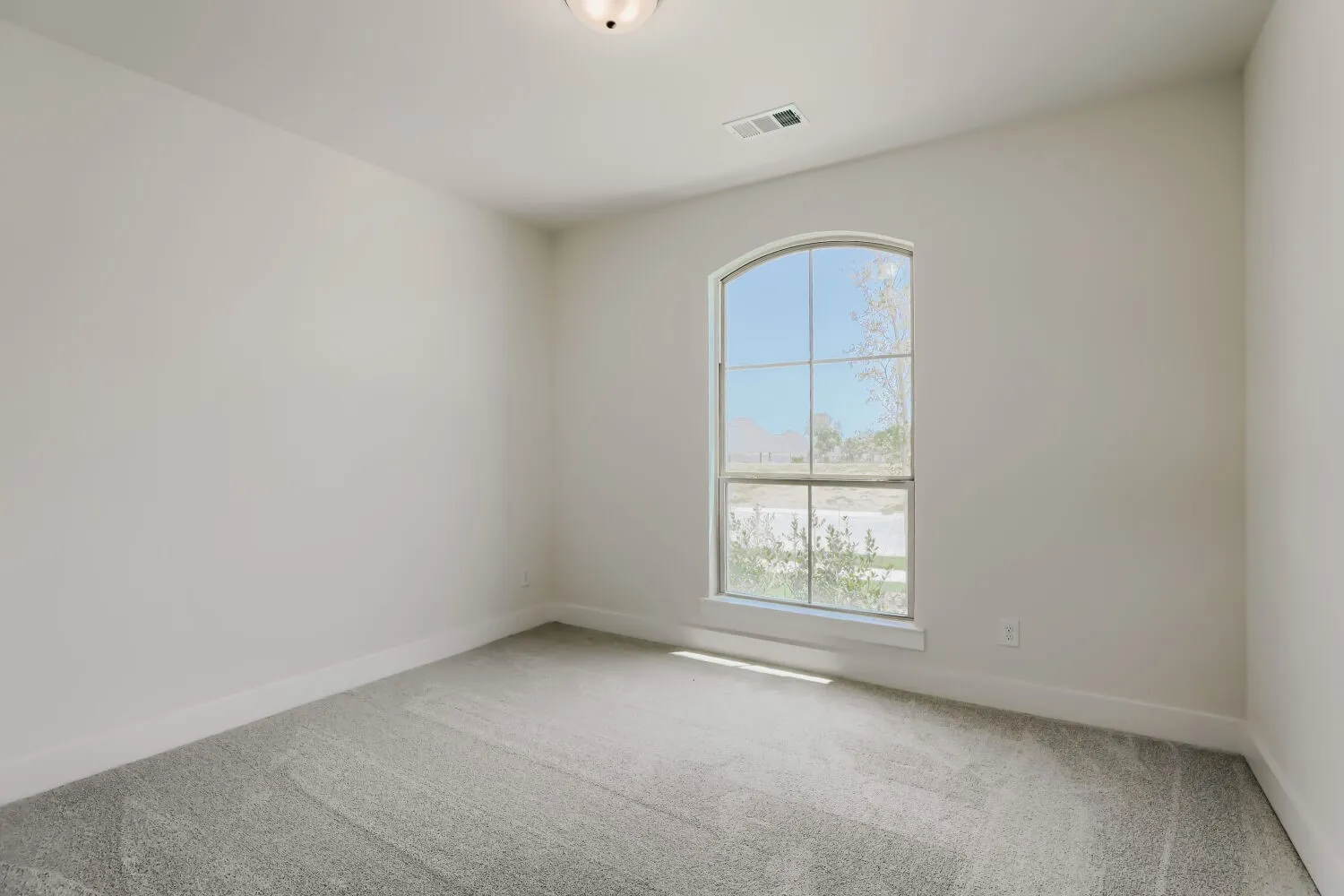 Arched window with exterior views, light gray carpeting, neutral wall paint, and recessed ceiling fixture