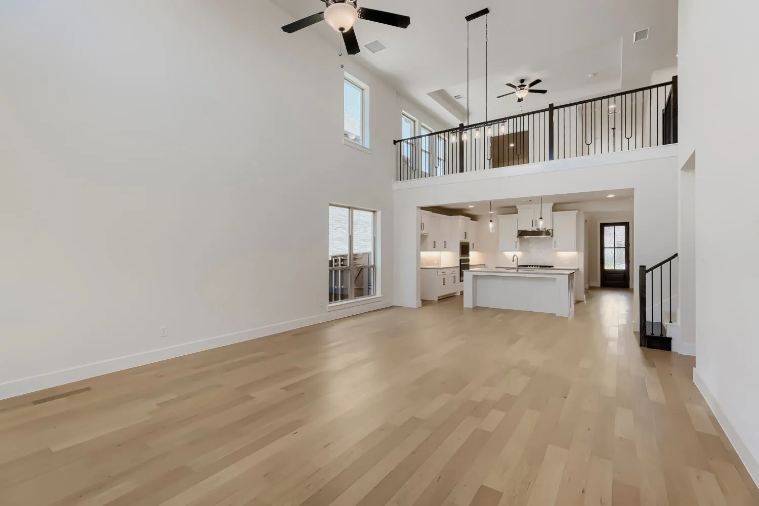Open-concept living space featuring high ceilings, wood-finish flooring, and a modern kitchen with a large island