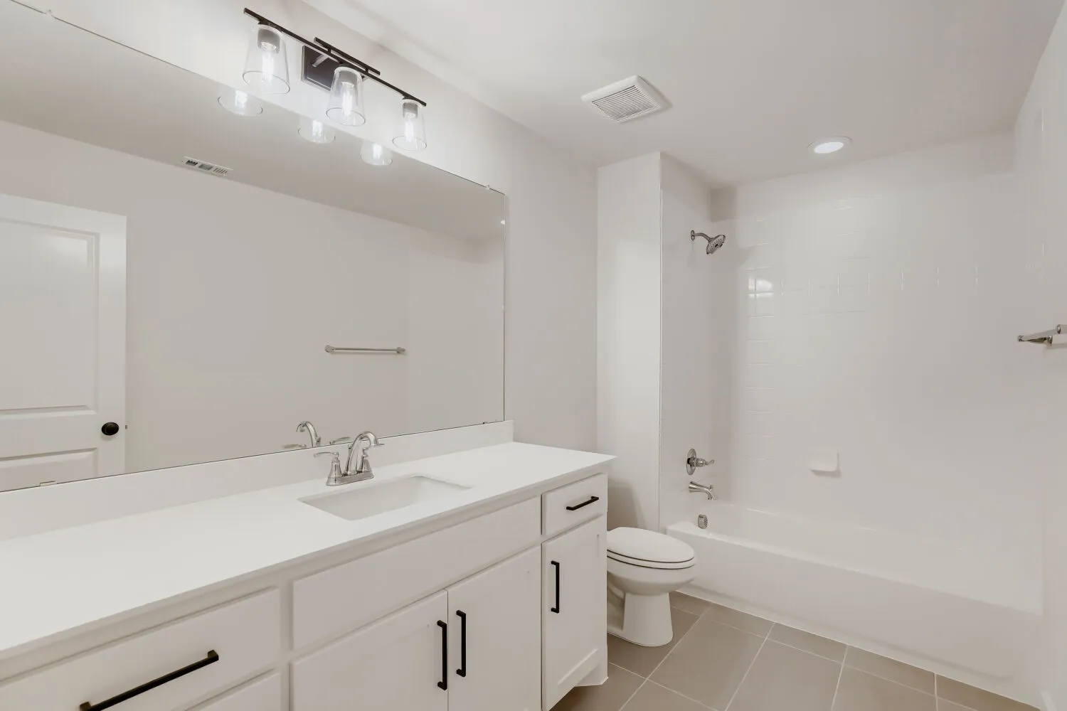 Bathroom featuring a vanity with an undermount sink, a wide mirror, a tub/shower combination with subway tile surround, and neutral tile flooring