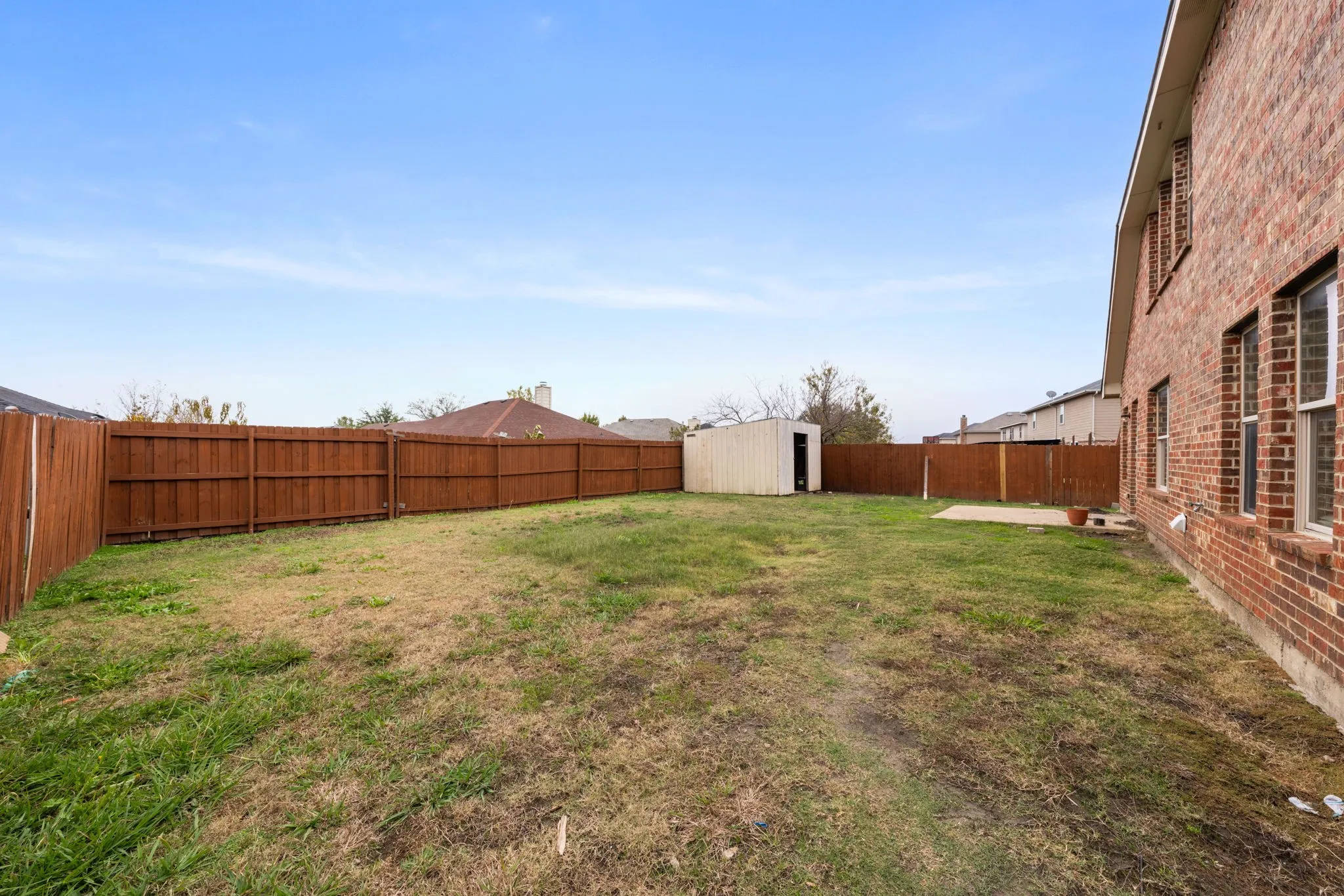Fenced backyard with a storage shed and a patio area