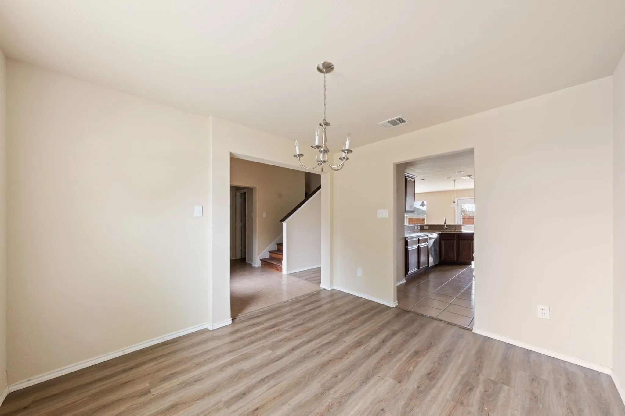 Unfurnished dining area with a chandelier, stairway, and light wood-style floors