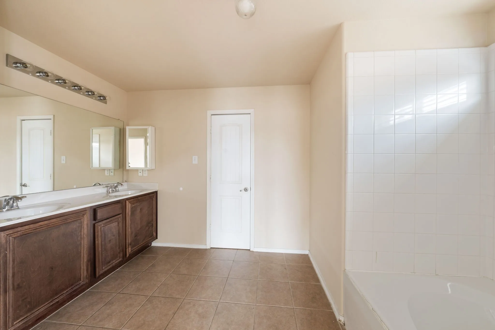 Full bath with double vanity and light tile patterned flooring