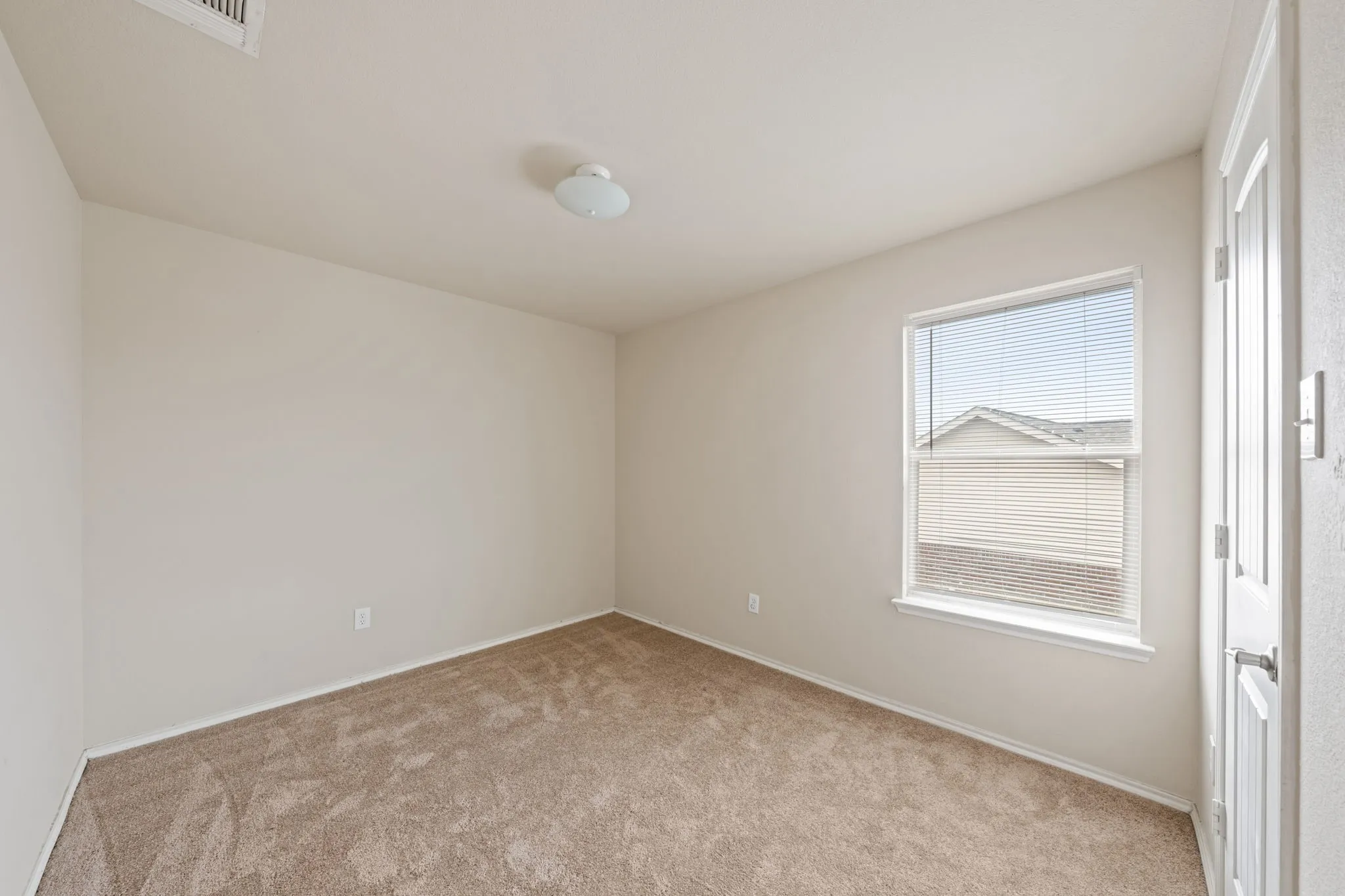 Empty room with light colored carpet and baseboards