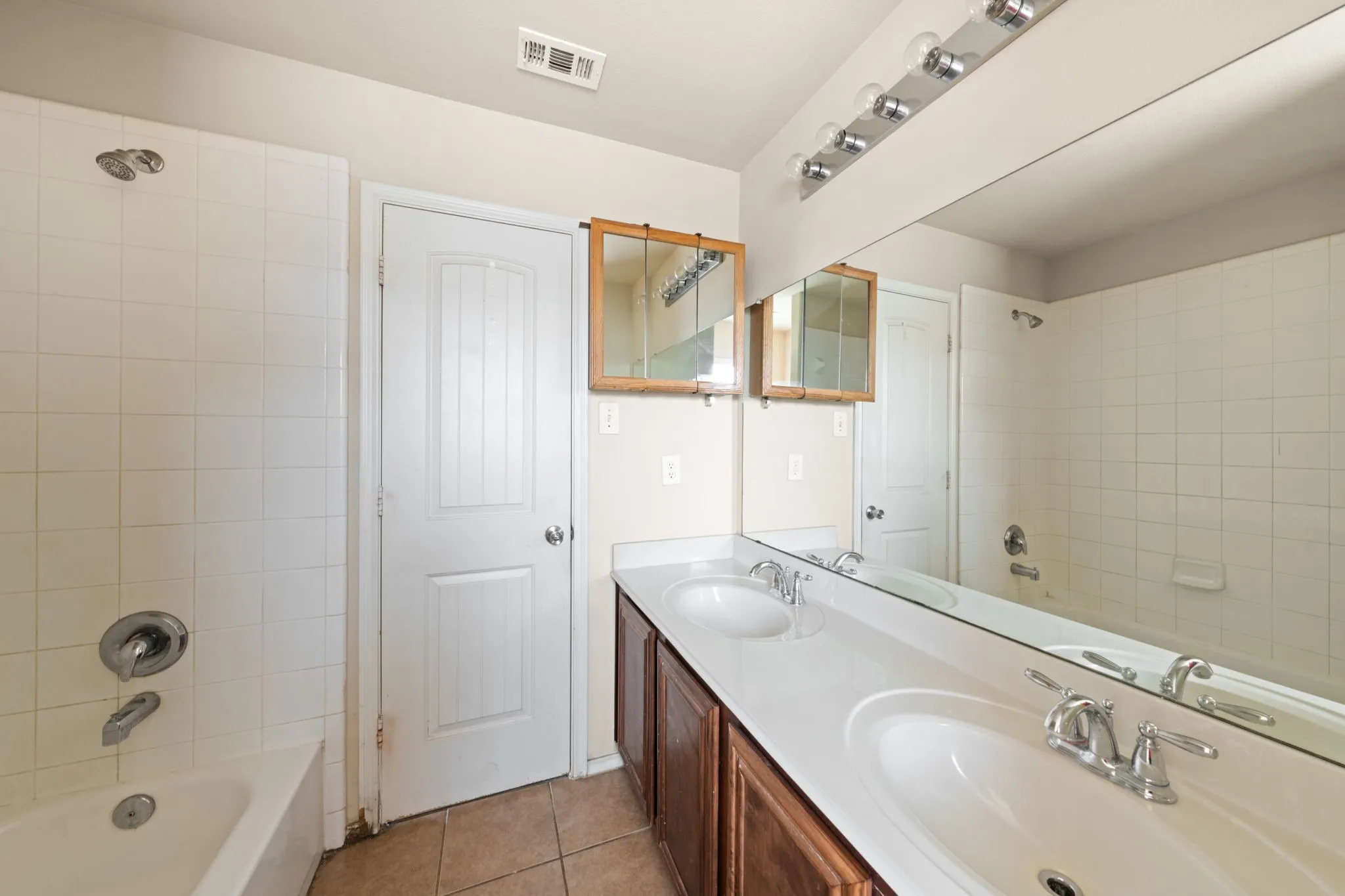 Bathroom featuring shower / washtub combination, double vanity, and light tile patterned flooring