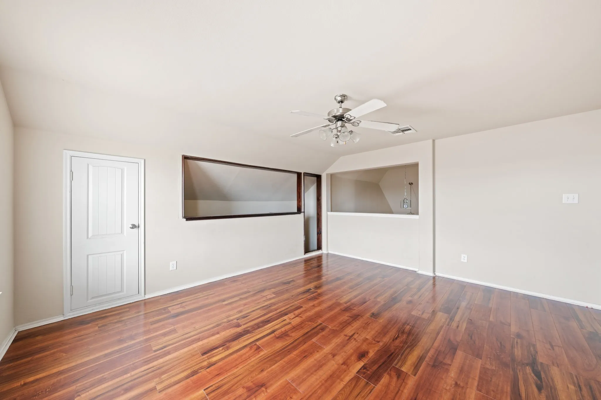 Empty room with vaulted ceiling, wood finished floors, and ceiling fan