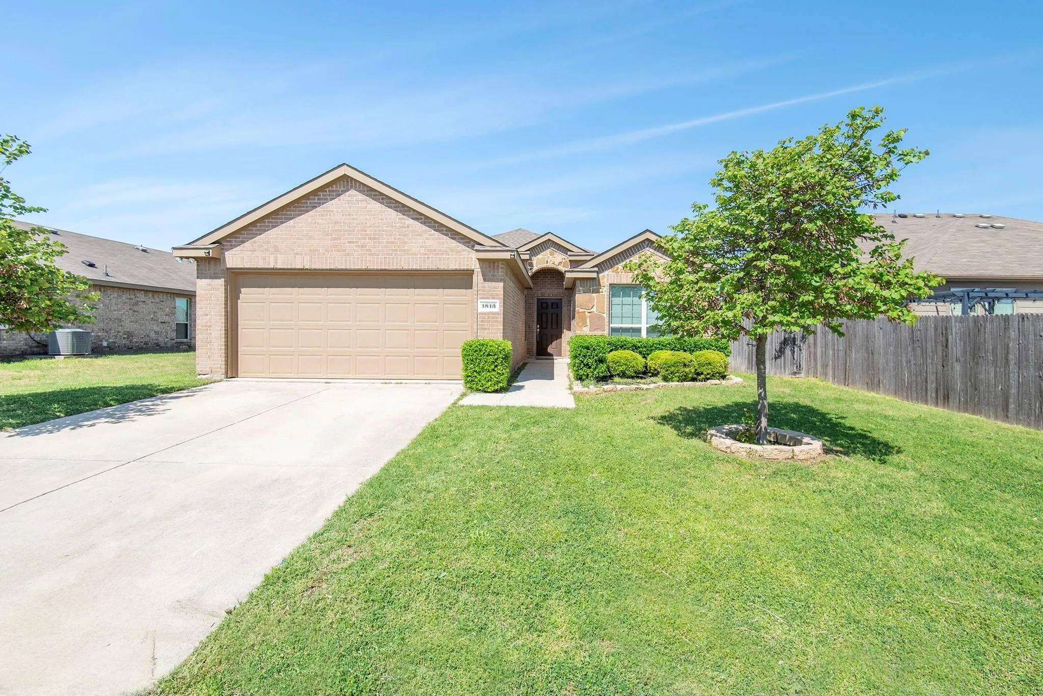 Ranch-style home featuring brick siding, driveway, and a garage