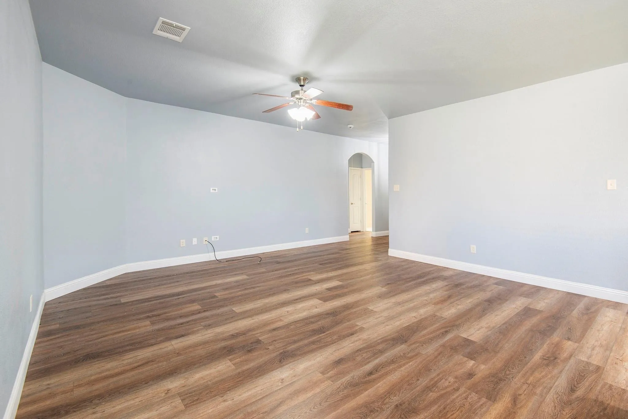 Spare room featuring arched walkways, wood finished floors, and ceiling fan