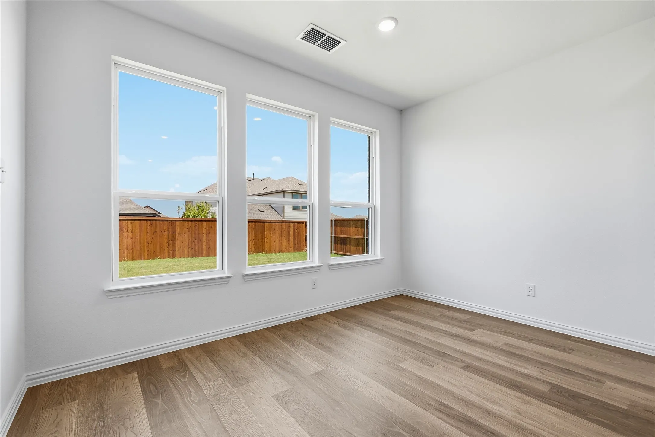 Room with light wood-finish flooring, white walls, and white baseboards