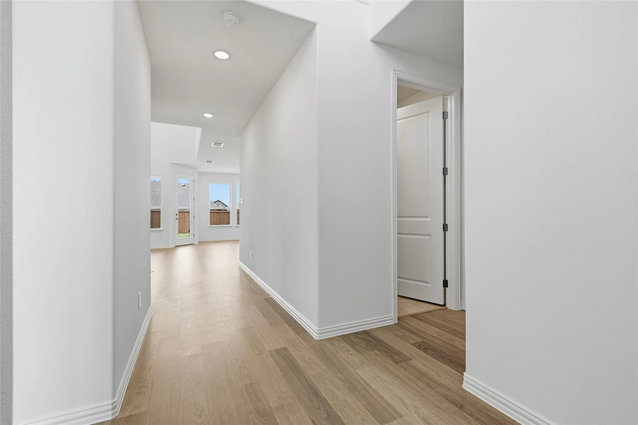 Hallway with wood-finish flooring, recessed lighting, and white baseboards