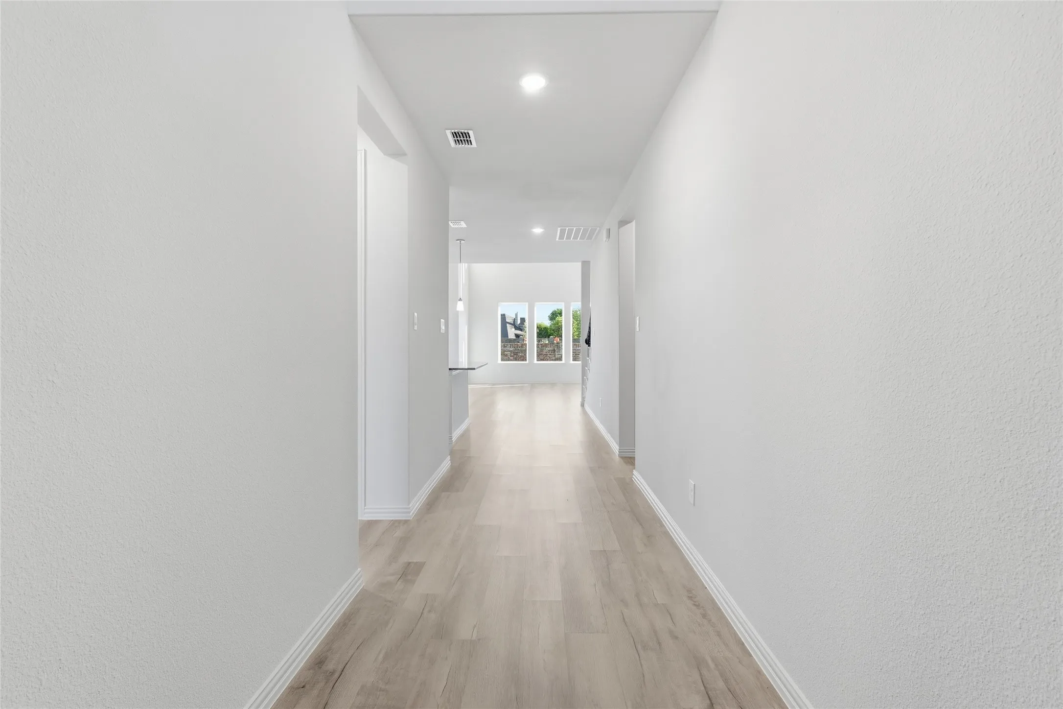 Hall featuring recessed lighting, light wood-style floors, and a textured wall